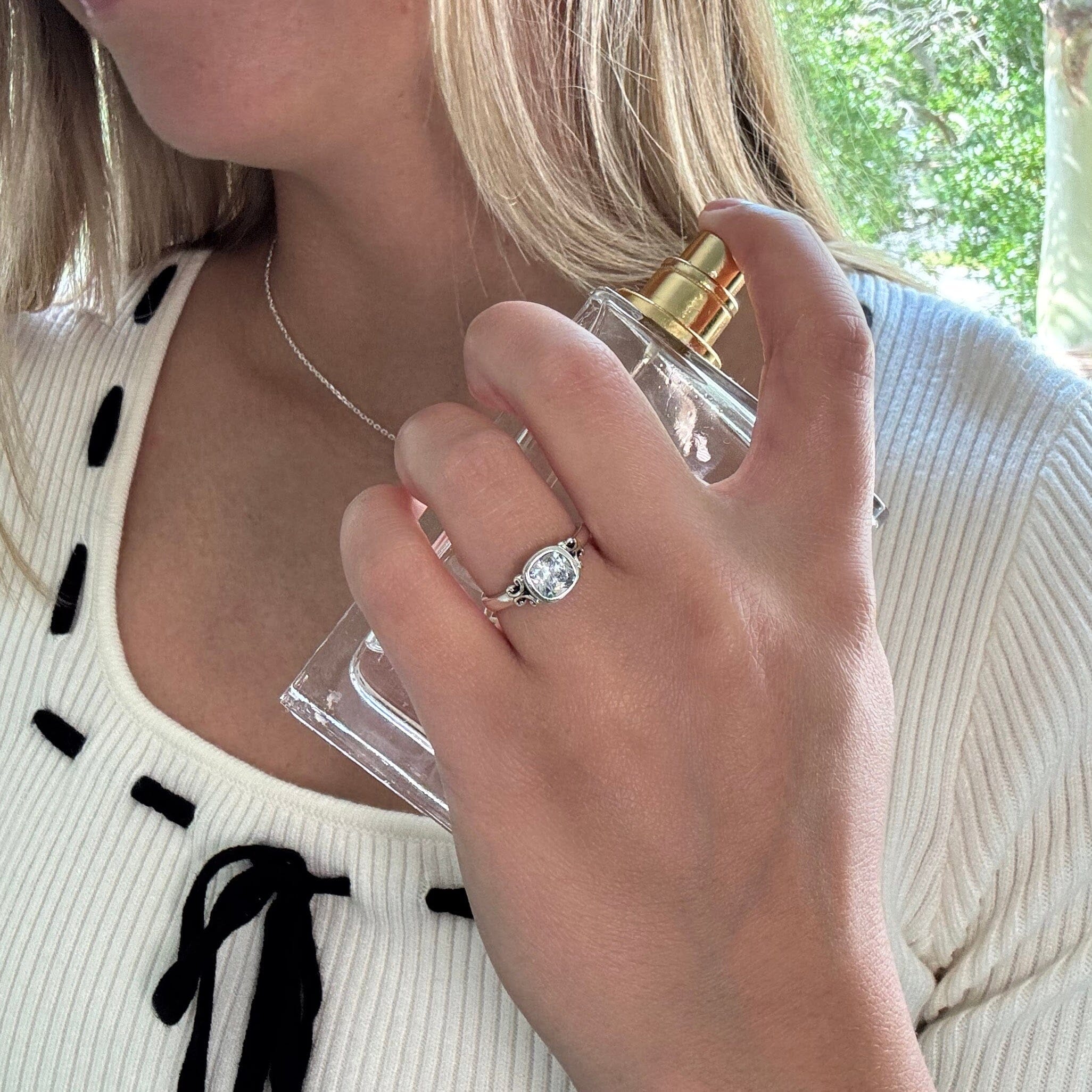 dainty sterling silver Alina Ring featuring scroll work on each side of a bezel-set cushion cut cz