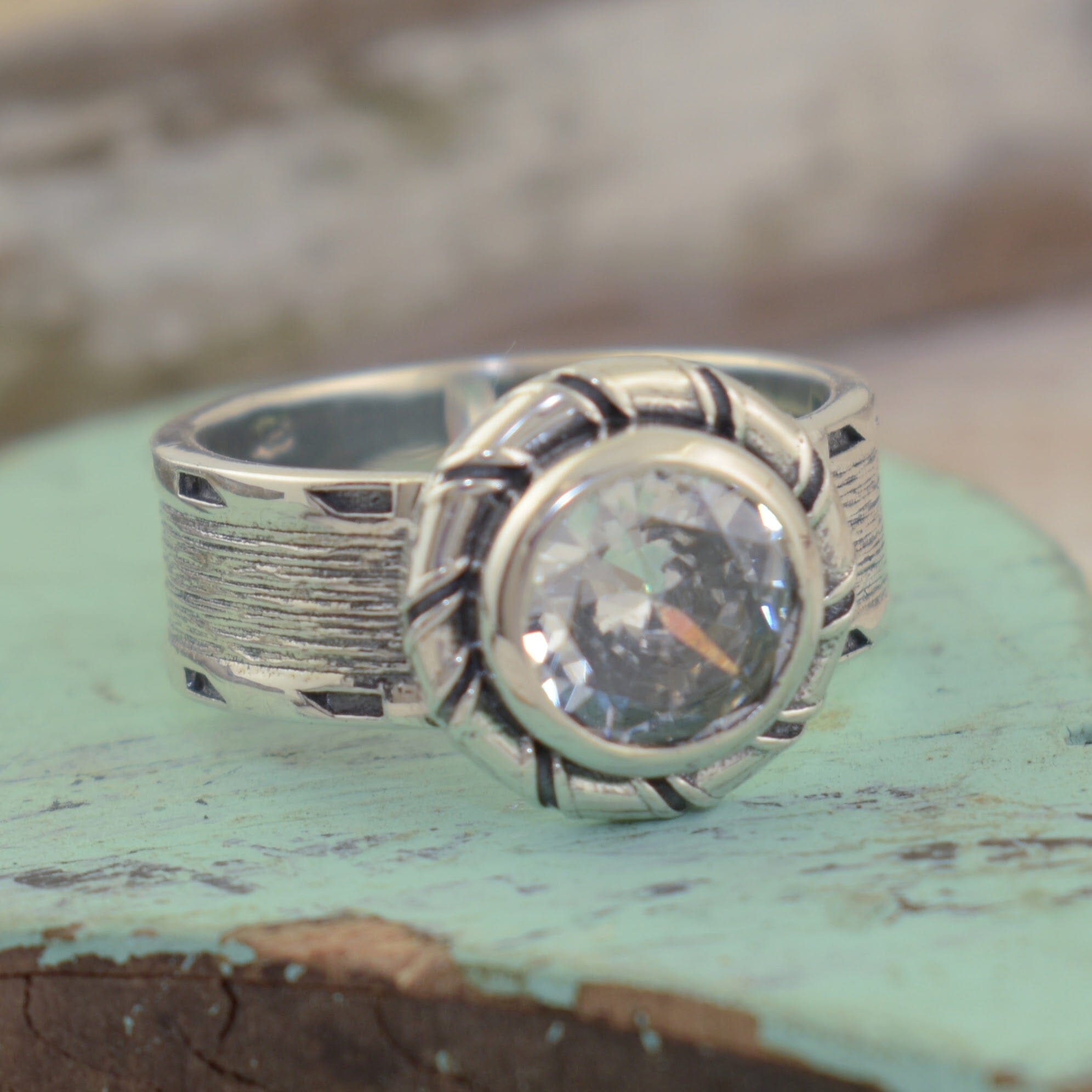 wider band with a brushed look on the side and a CZ stone in the center