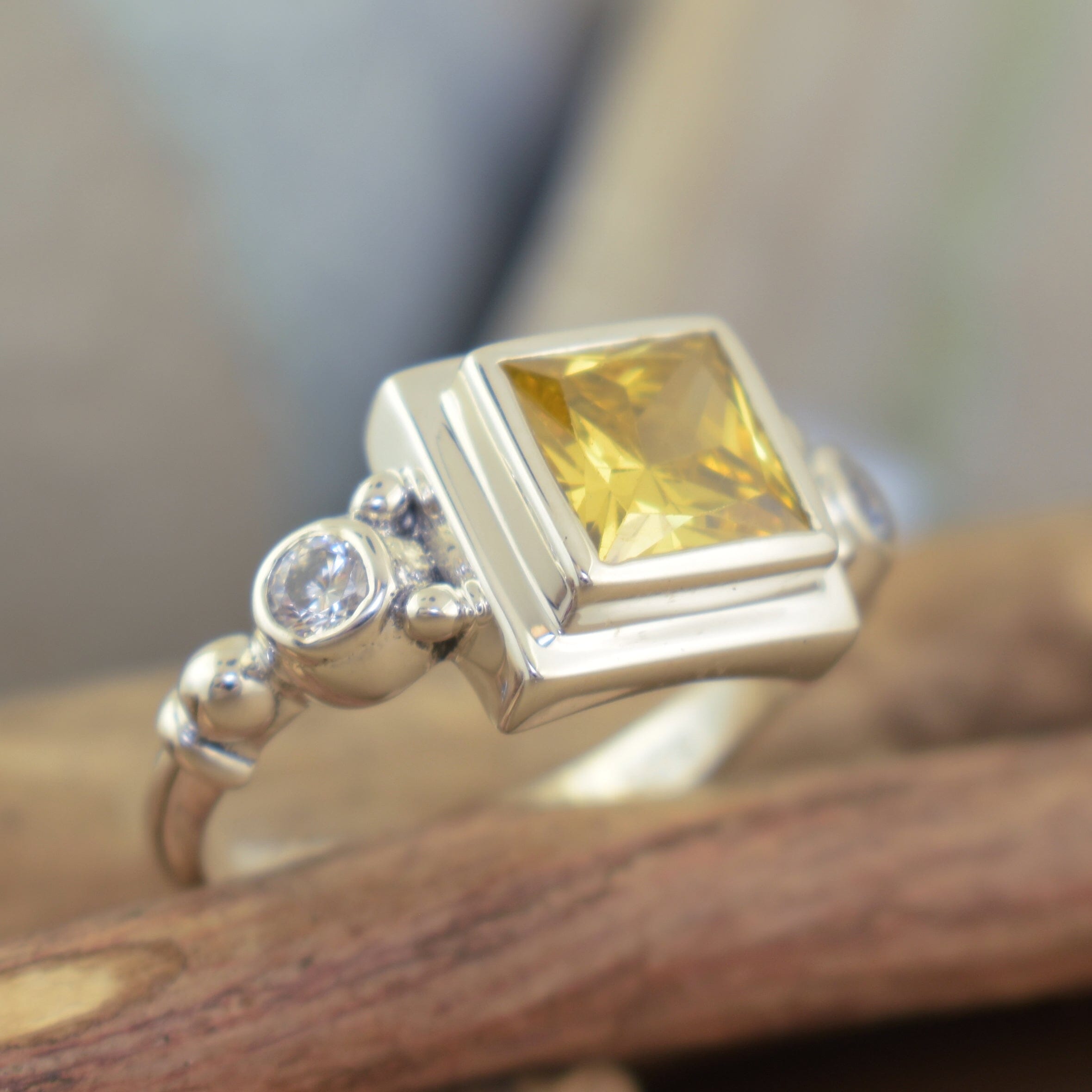 unique silver designer ring featuring princess-cut saffron and two round clear cubic zirconia stones