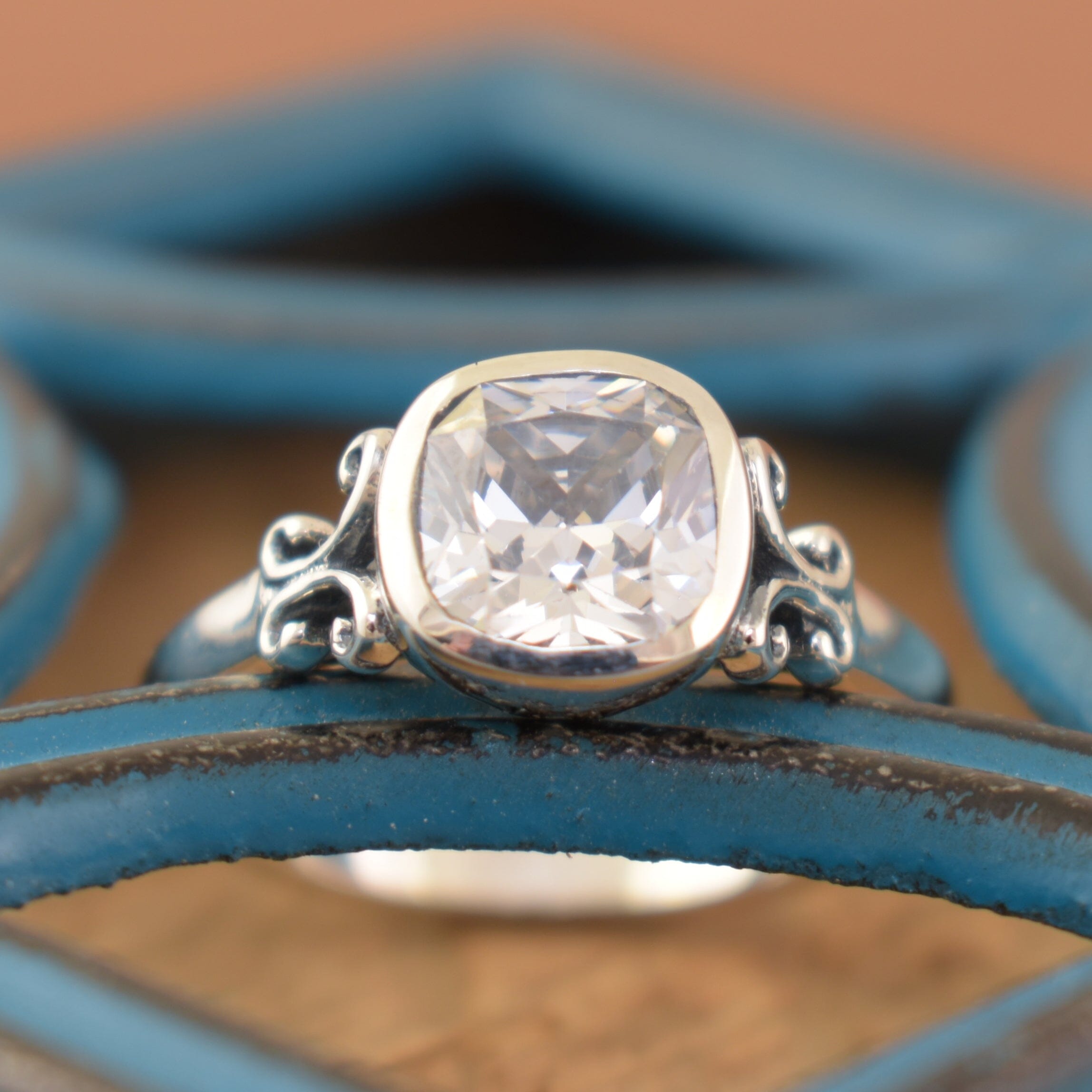 Designer-inspired sterling silver ring with scrollwork band and cushion cut cz