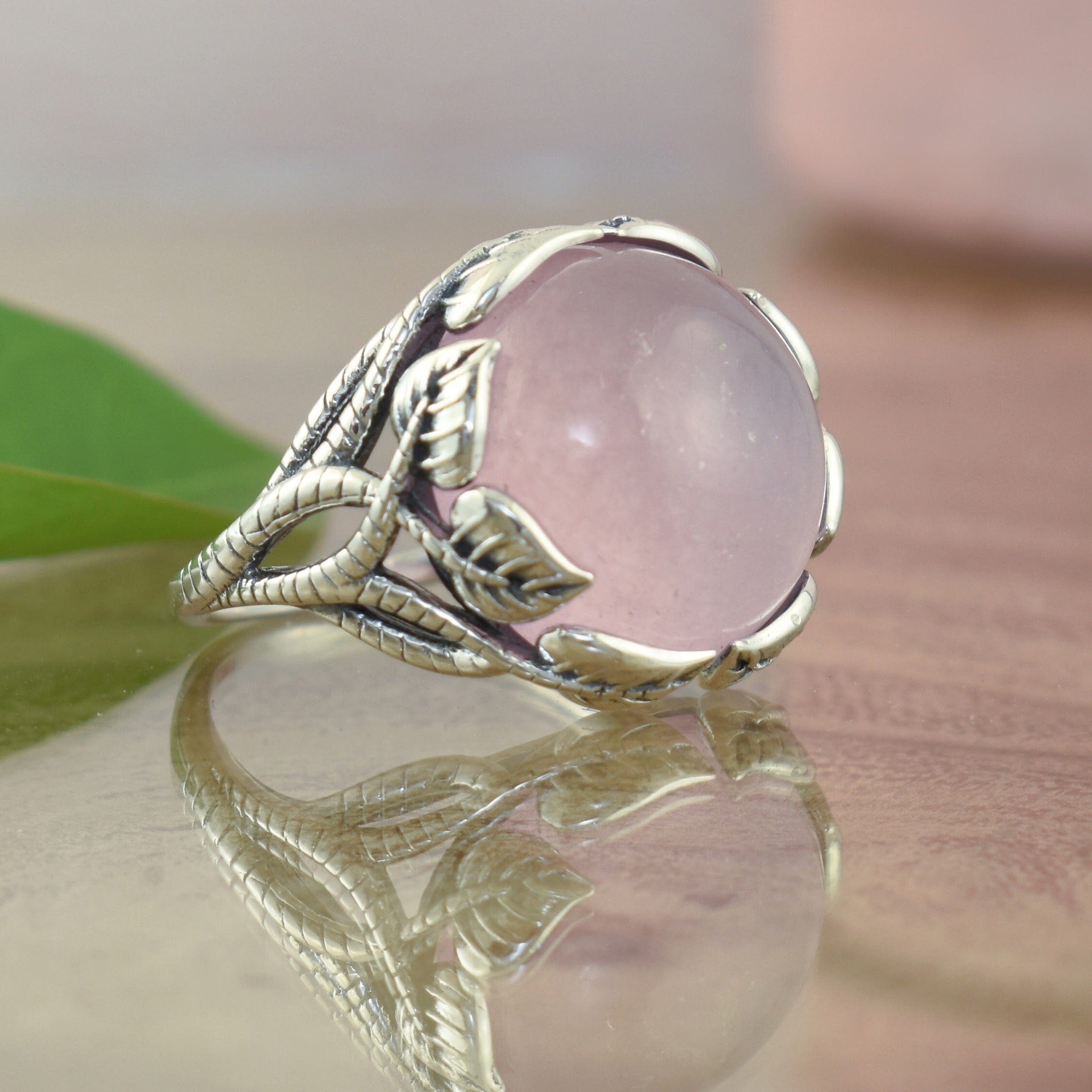.925 sterling silver ring with leaf detail featuring a large round pink stone