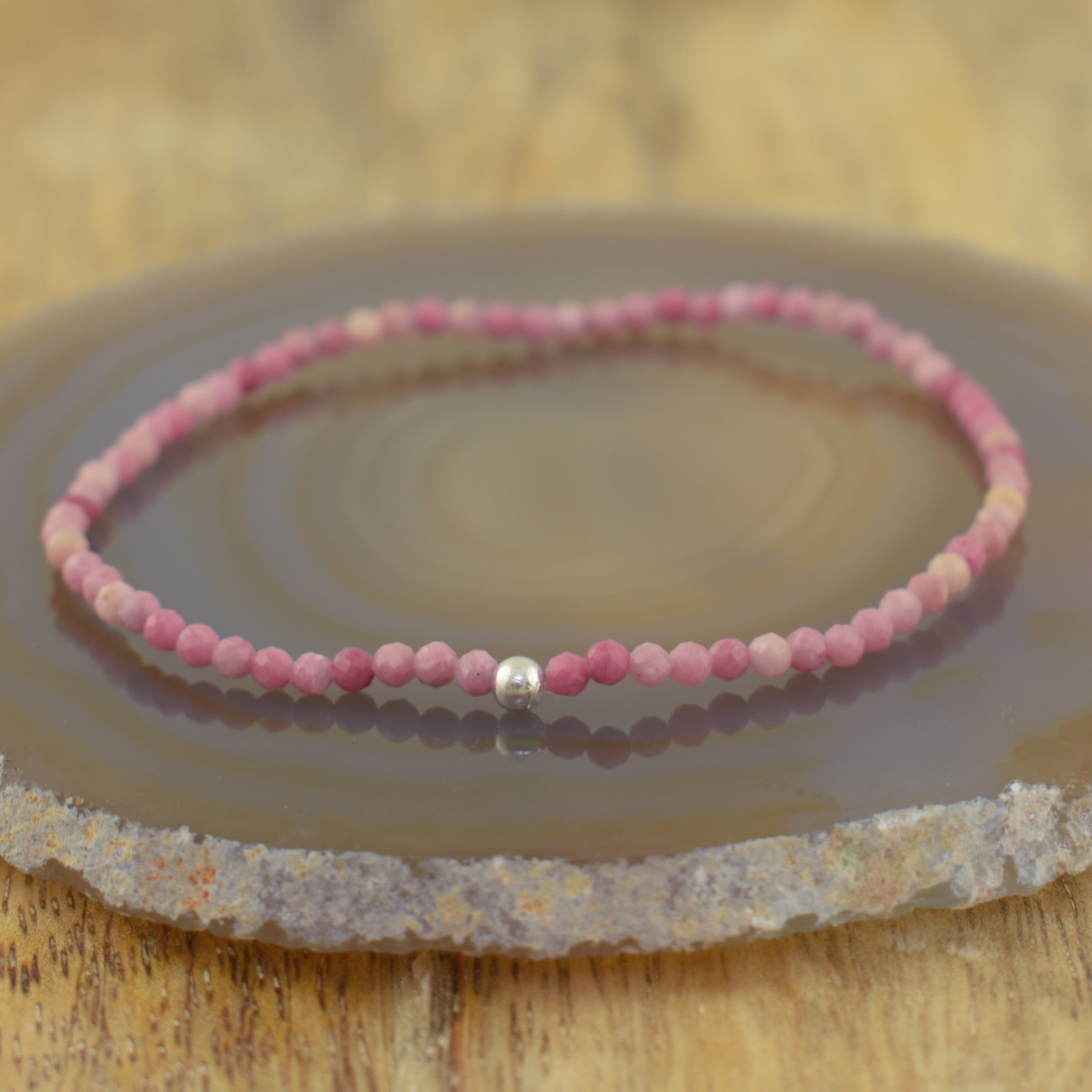 a beaded stretch bracelet made of handcrafted pink beads in a variety of shades, with a single silver accent bead