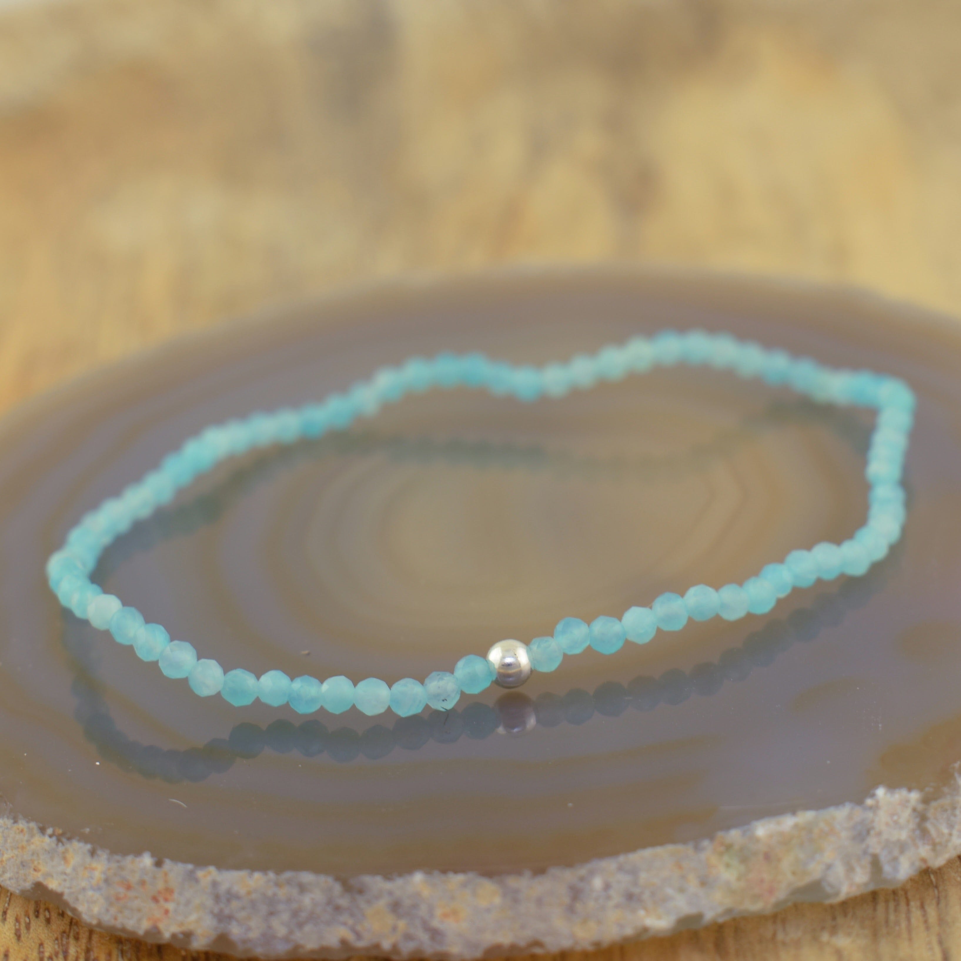 a stretchy beaded bracelet made of light blue faceted beads with a single silver spacer bead