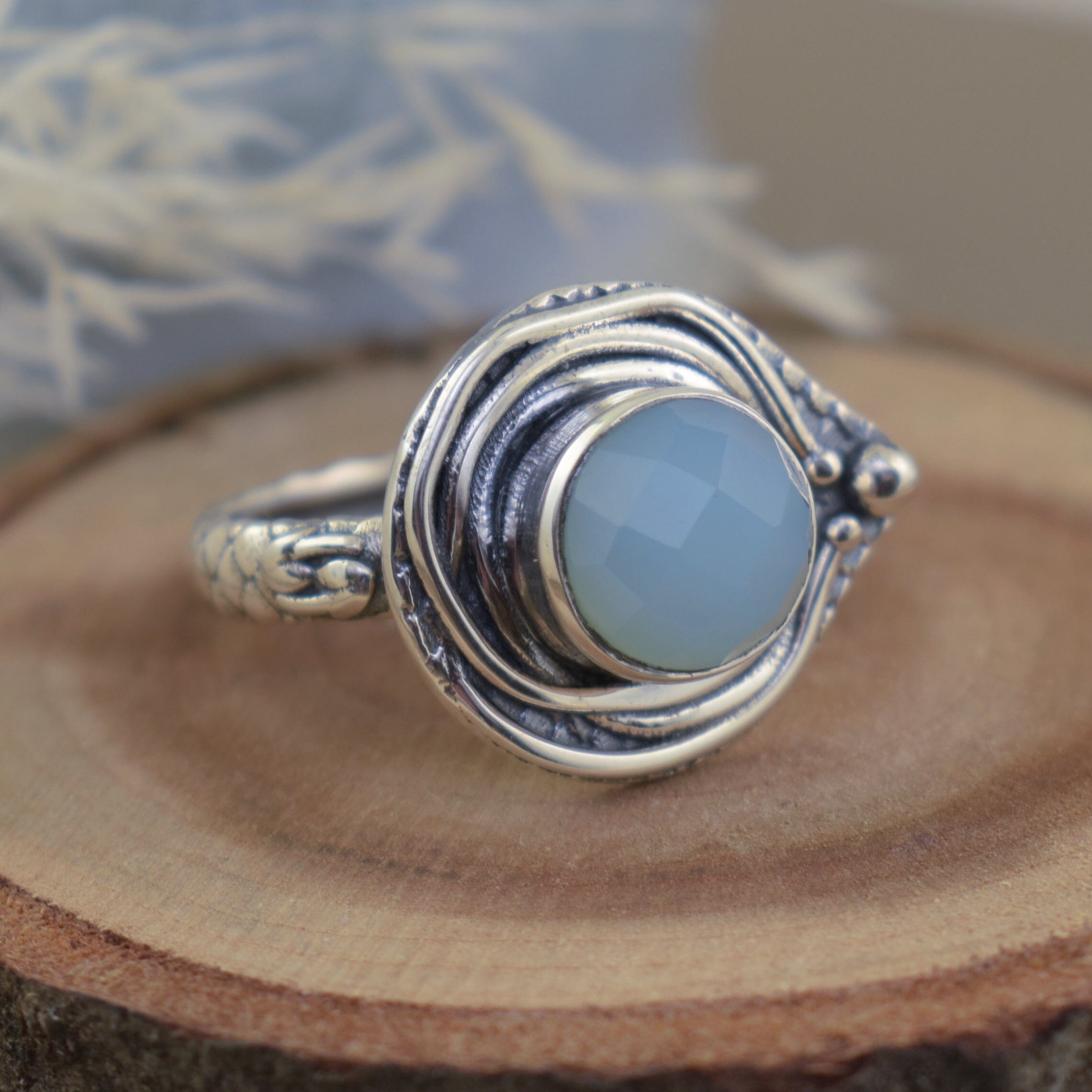 sterling silver ring featuring a round face with a center aqua chalcedony stone