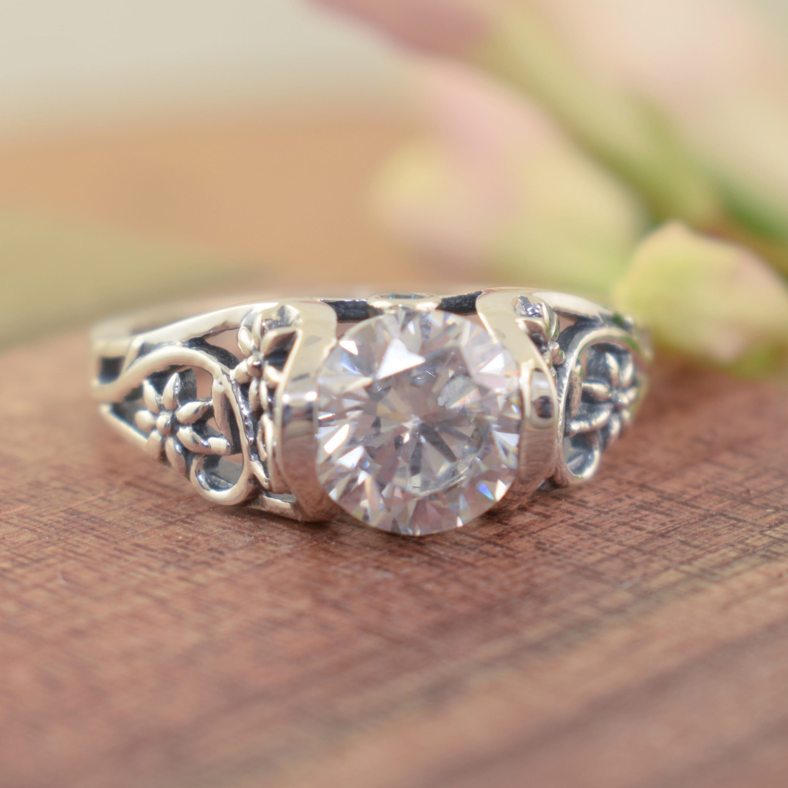 Round CZ stone ring with a detailed vine and flower band