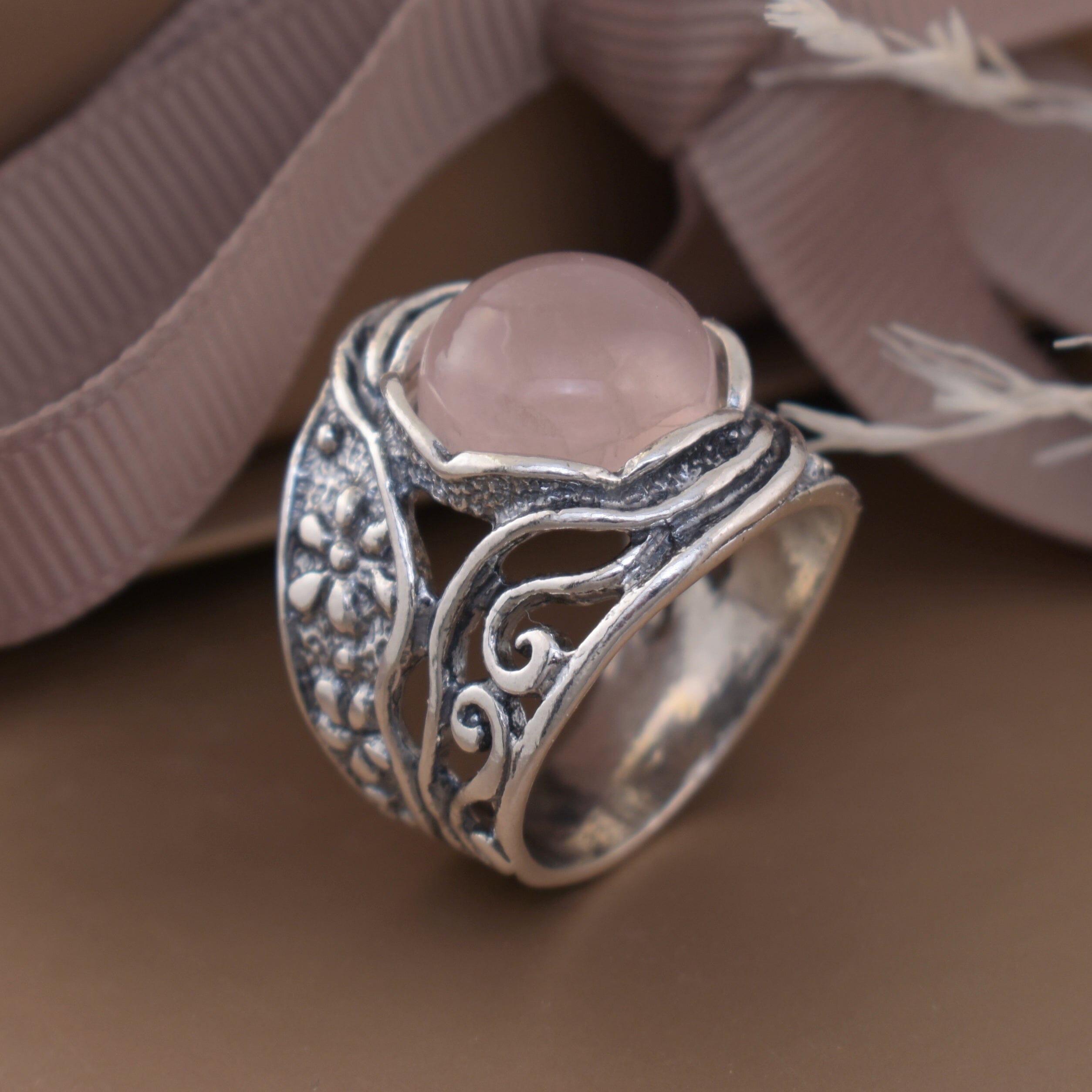 antiqued sterling silver ring featuring floral details and a pink center stone