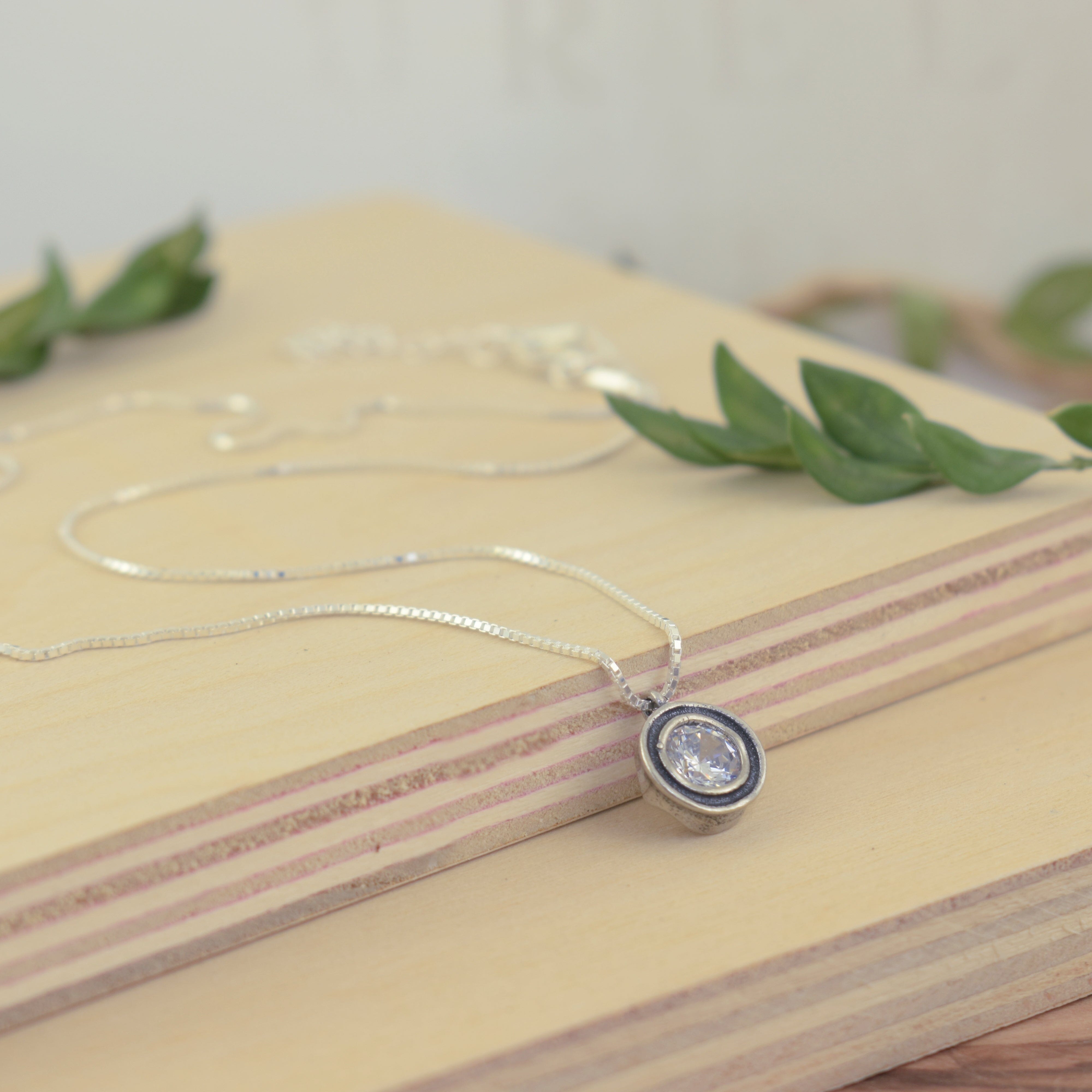 sterling silver necklace with a round silver pendant bezel set with a CZ center