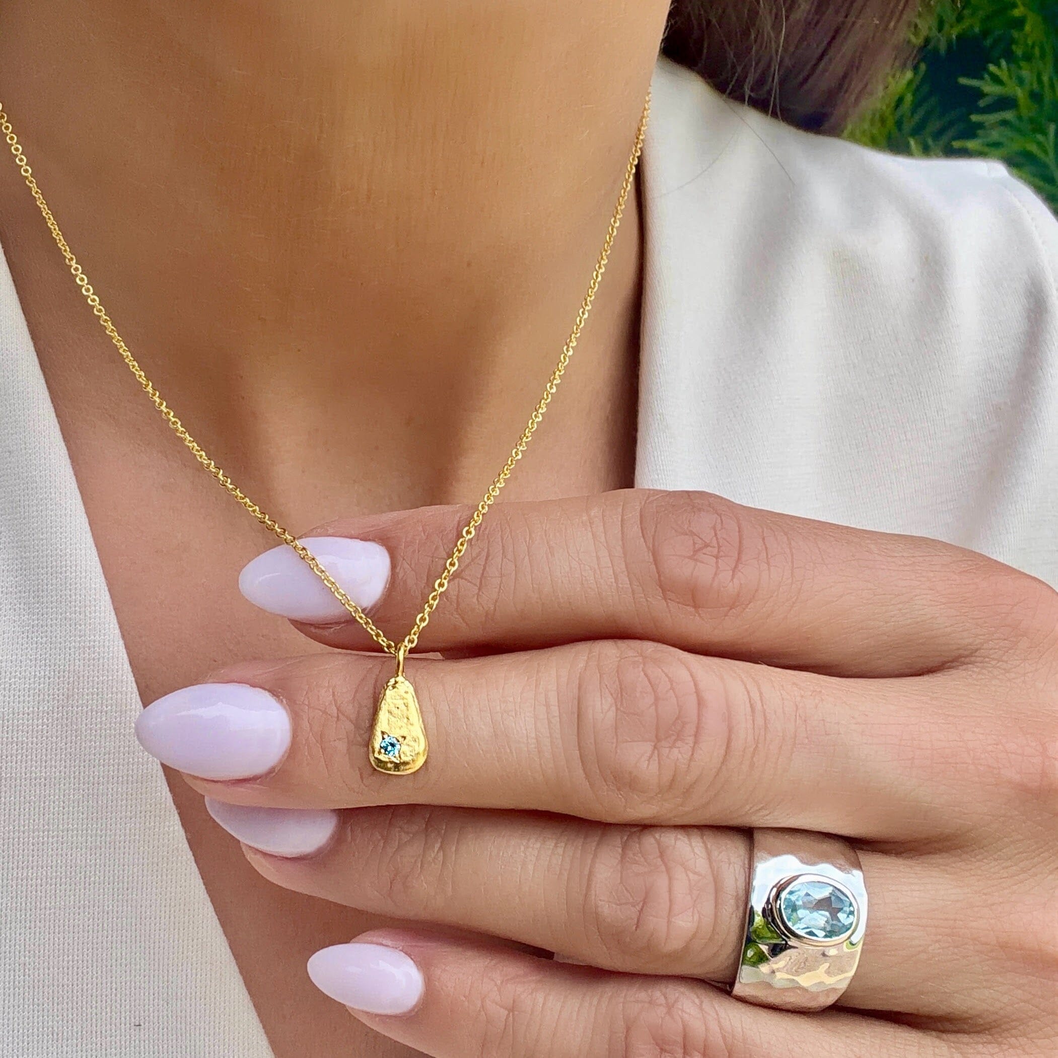 gold hammered pendant necklace with a blue cz
