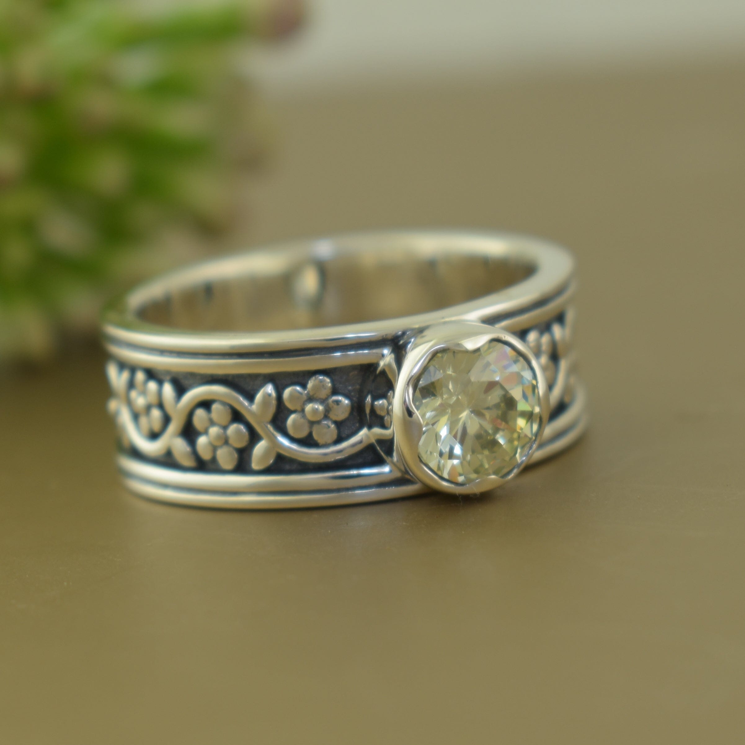 Silver ring with decorative band and central light green gemstone