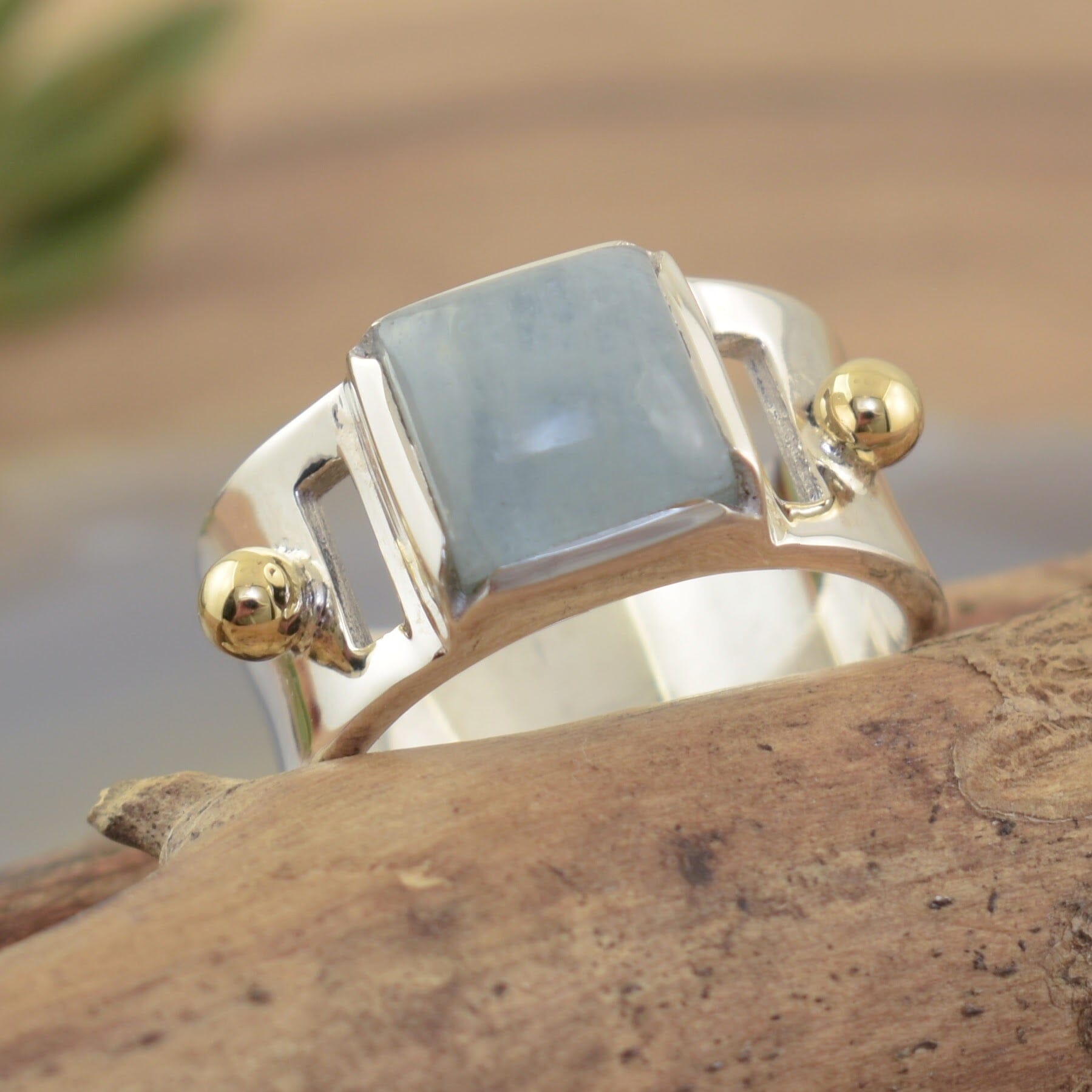 Sleek wide band ring with cutout details with a brass ball on each side