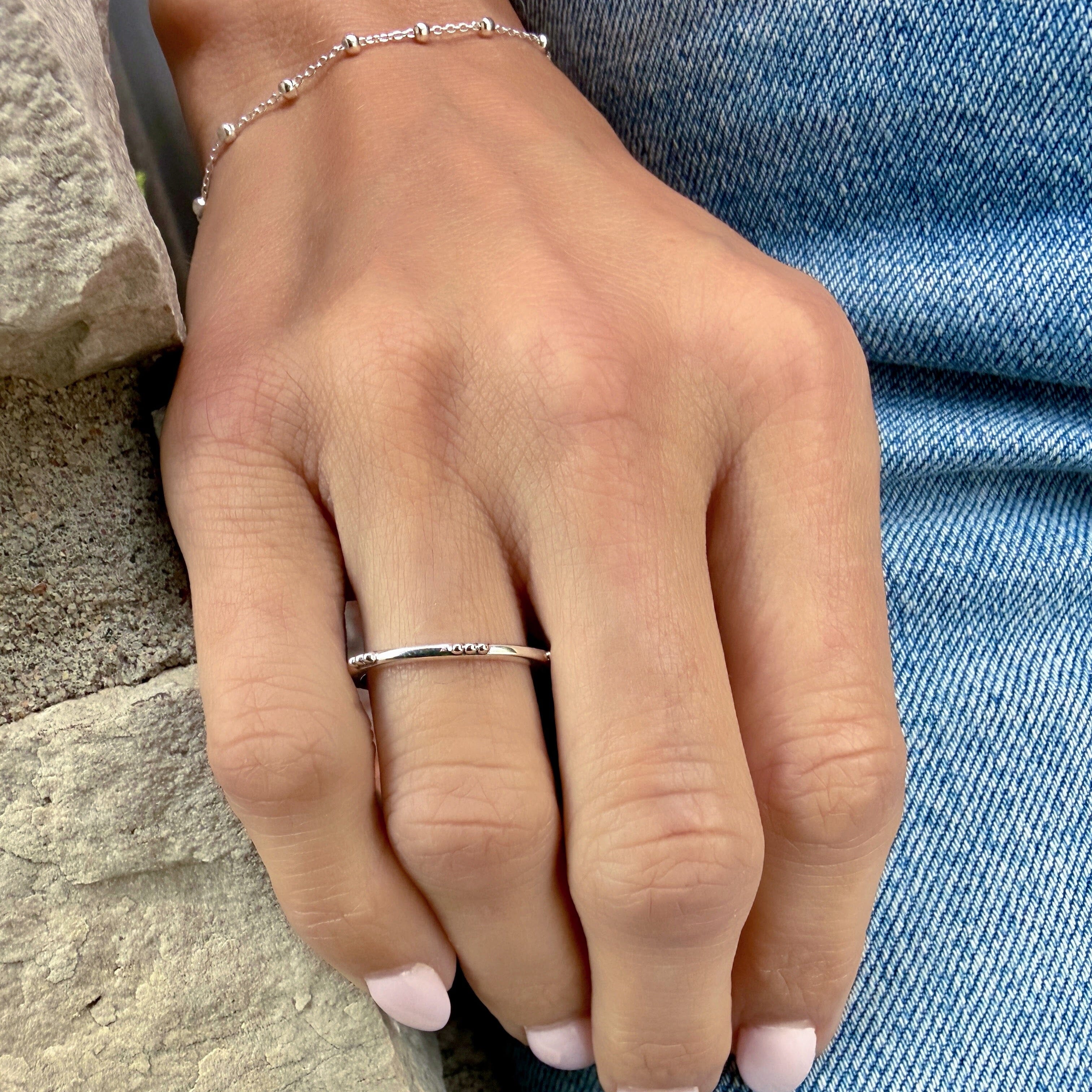 A model wearing a sterling silver thin band ring with little ball details spaced along the edge of the band