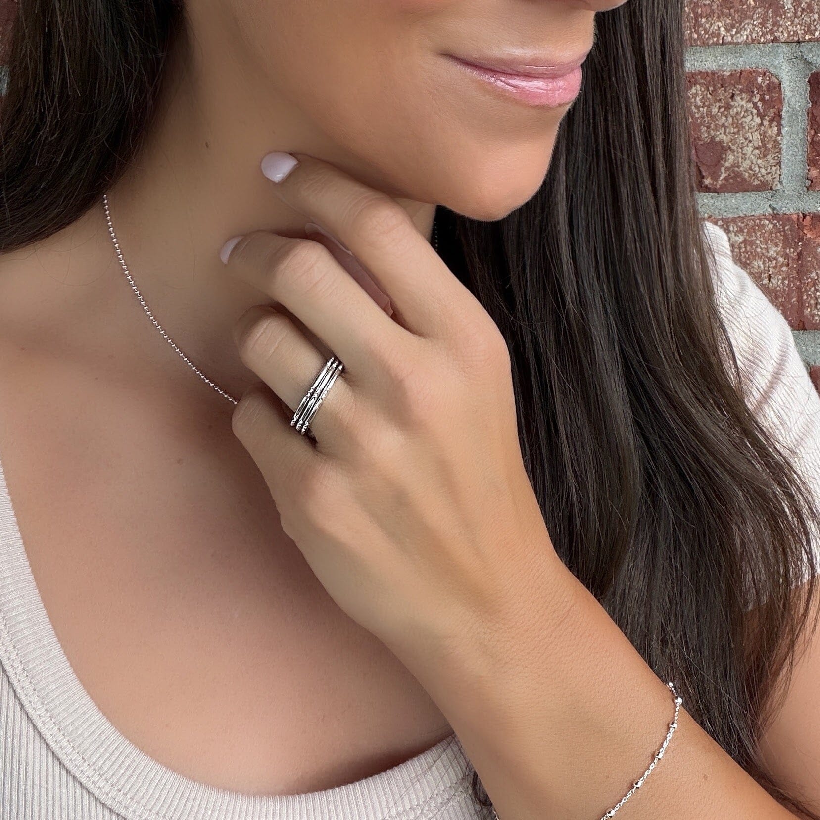 A model wearing a sterling silver thin band ring with little ball details spaced along the edge of the band