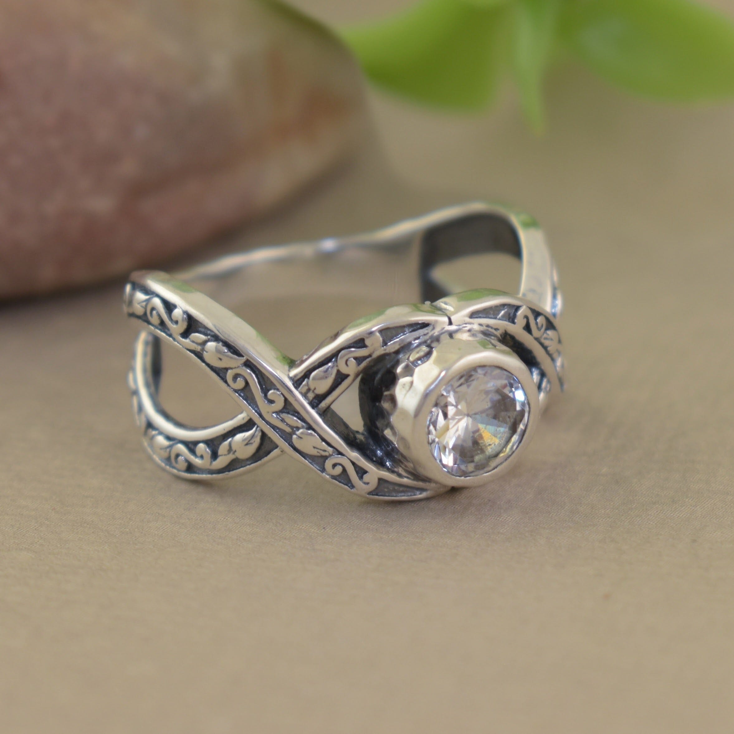 Sterling silver ring with delicate crisscross band adorned with intricate swirl details