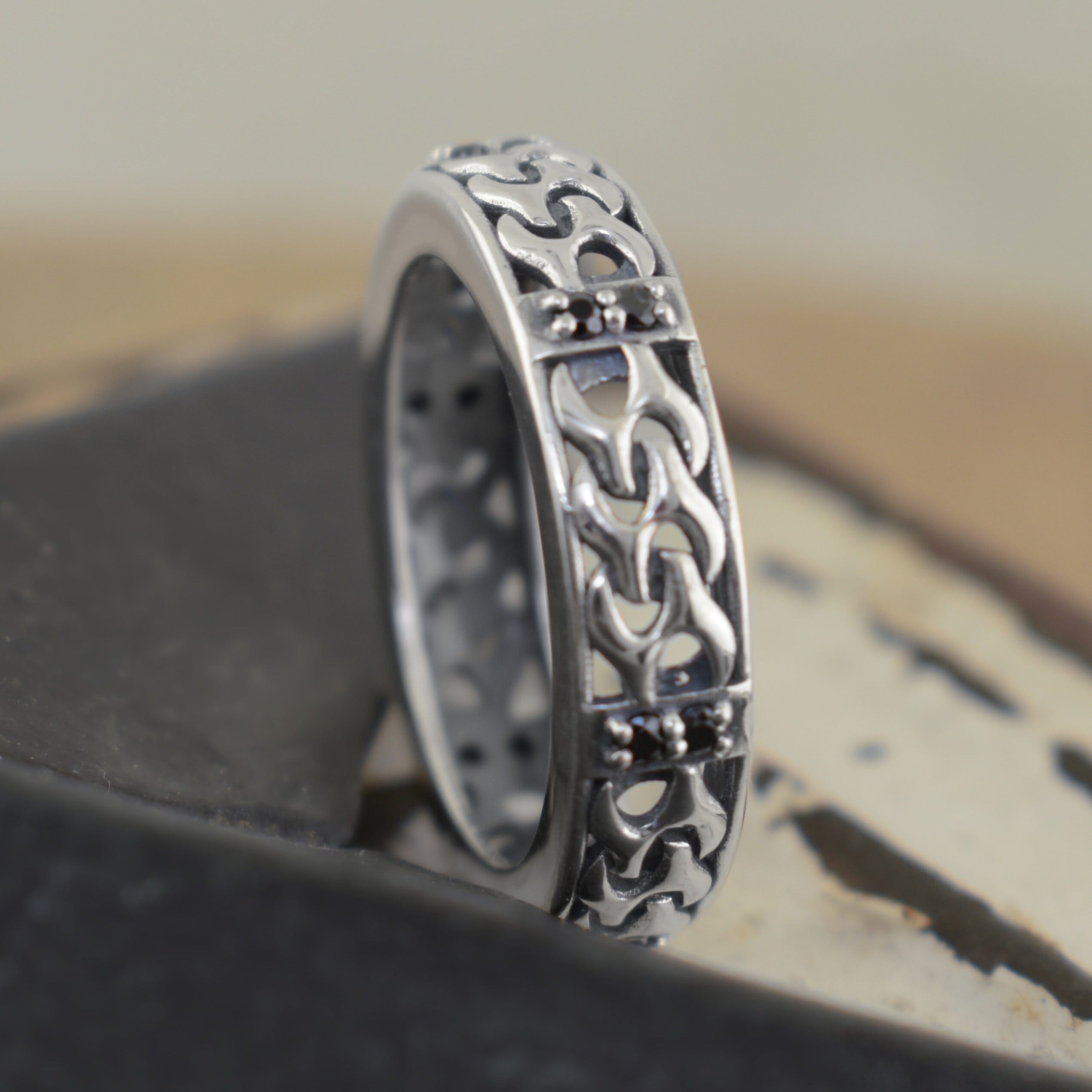 A sterling silver high polish ring, with small faceted black gemstones and a chain-shaped band