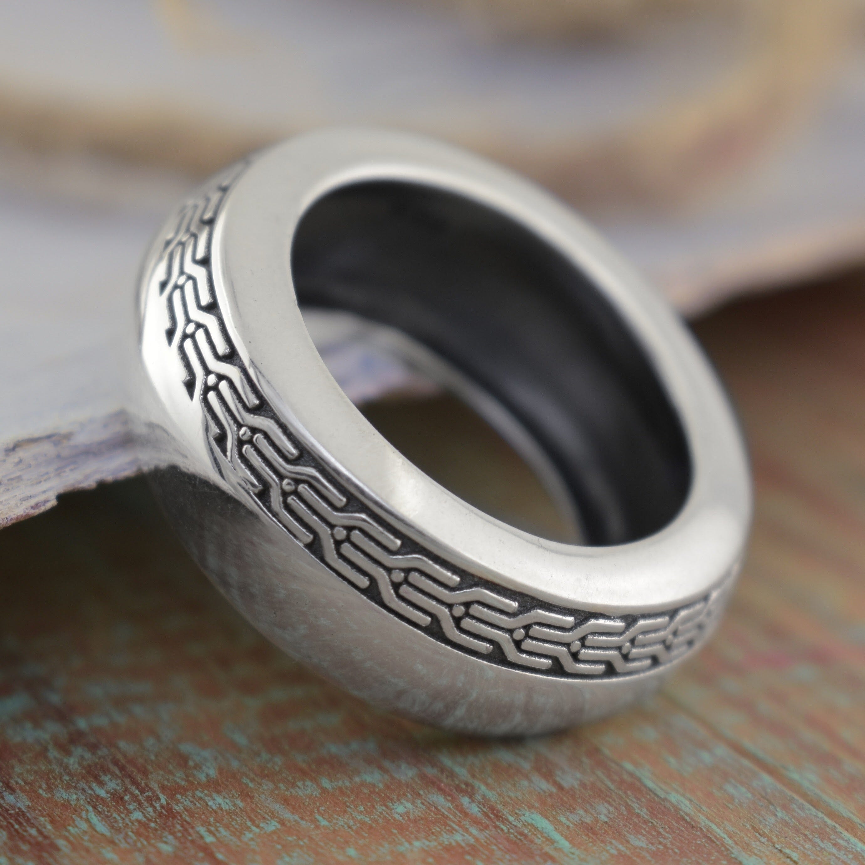 A sterling silver ring with an engraved circuit-like pattern on the outer band