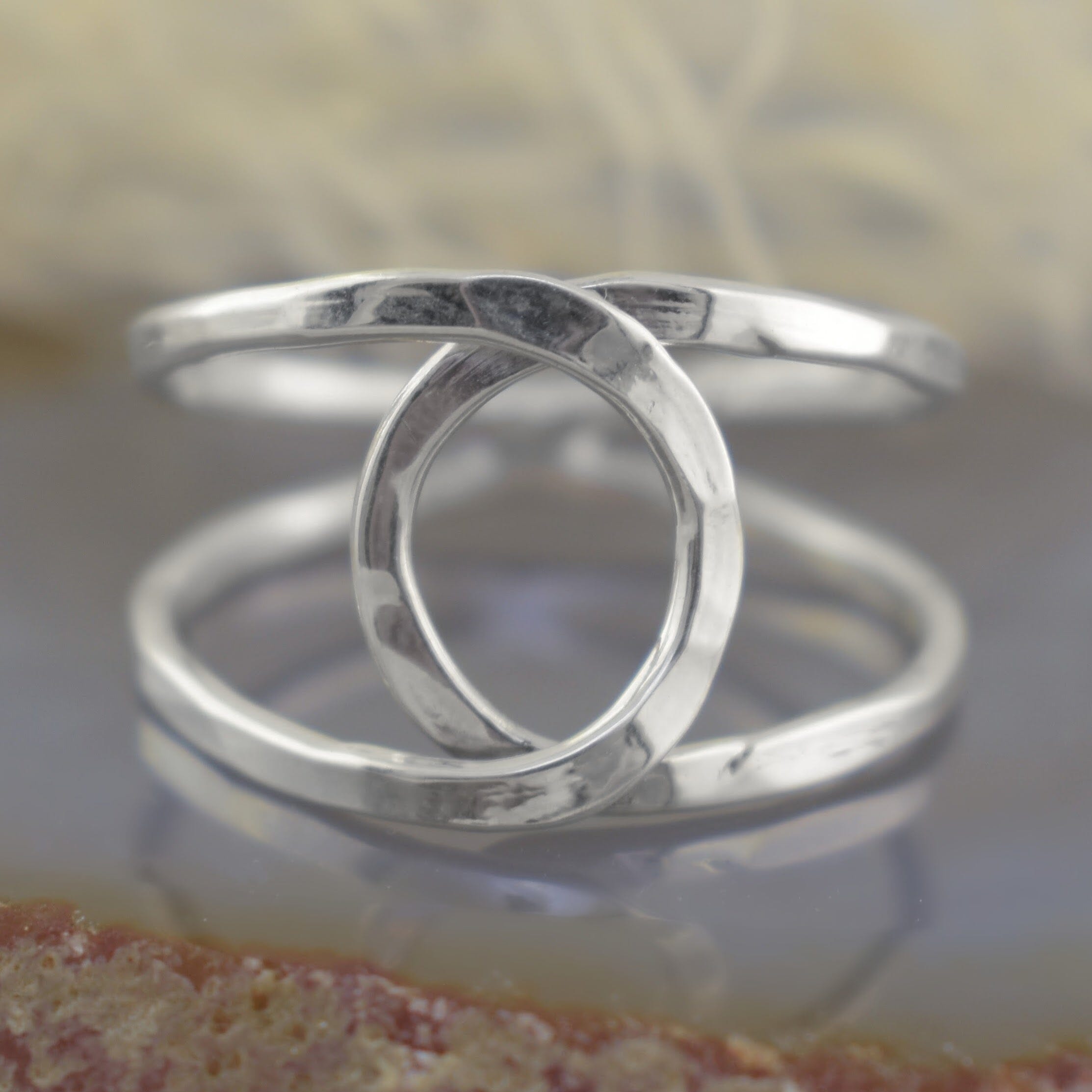 A polished sterling silver ring with 2 overlapping circular shapes and curved designs