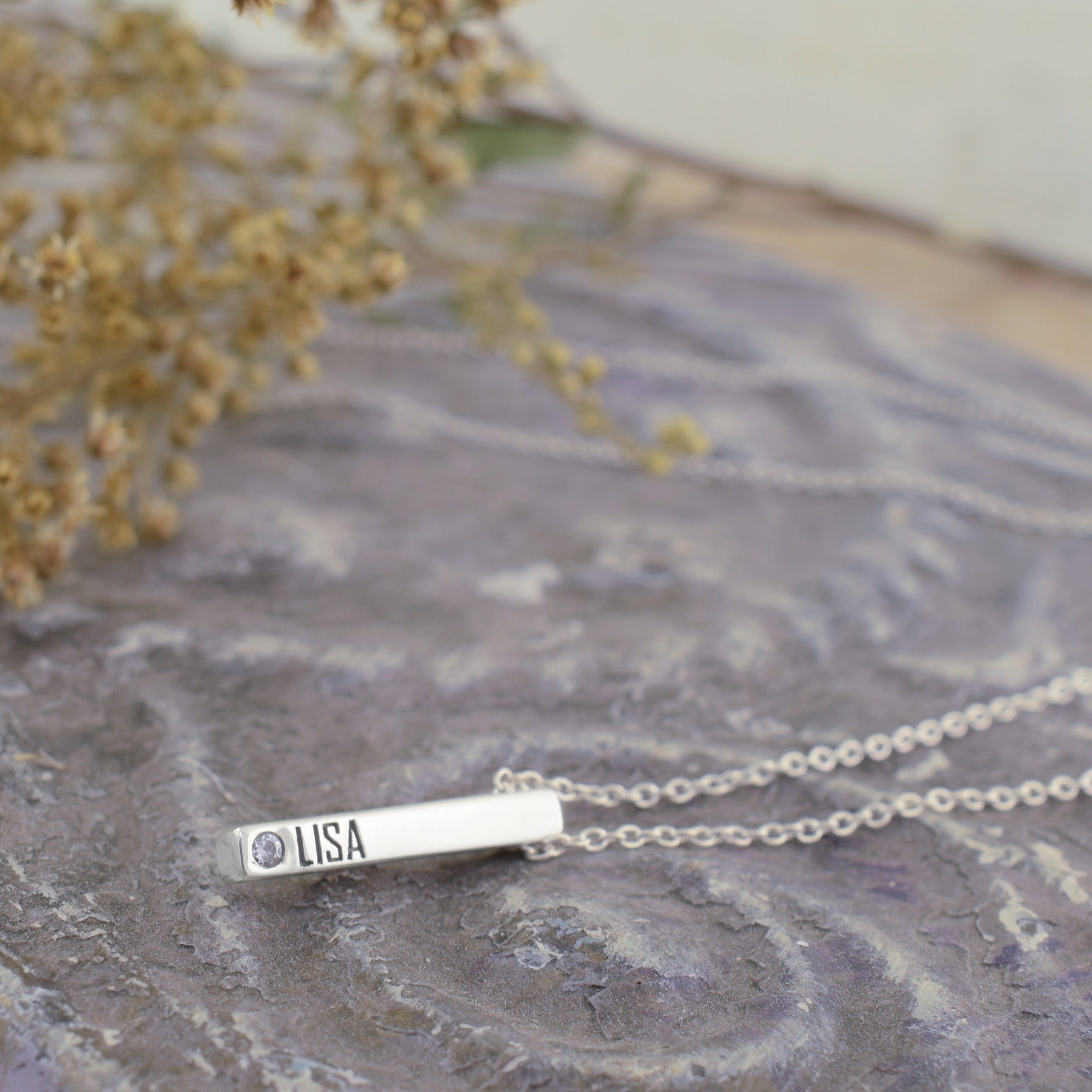 A sterling silver bar necklace engraved with the name 'LISA' and a small circular CZ gemstone