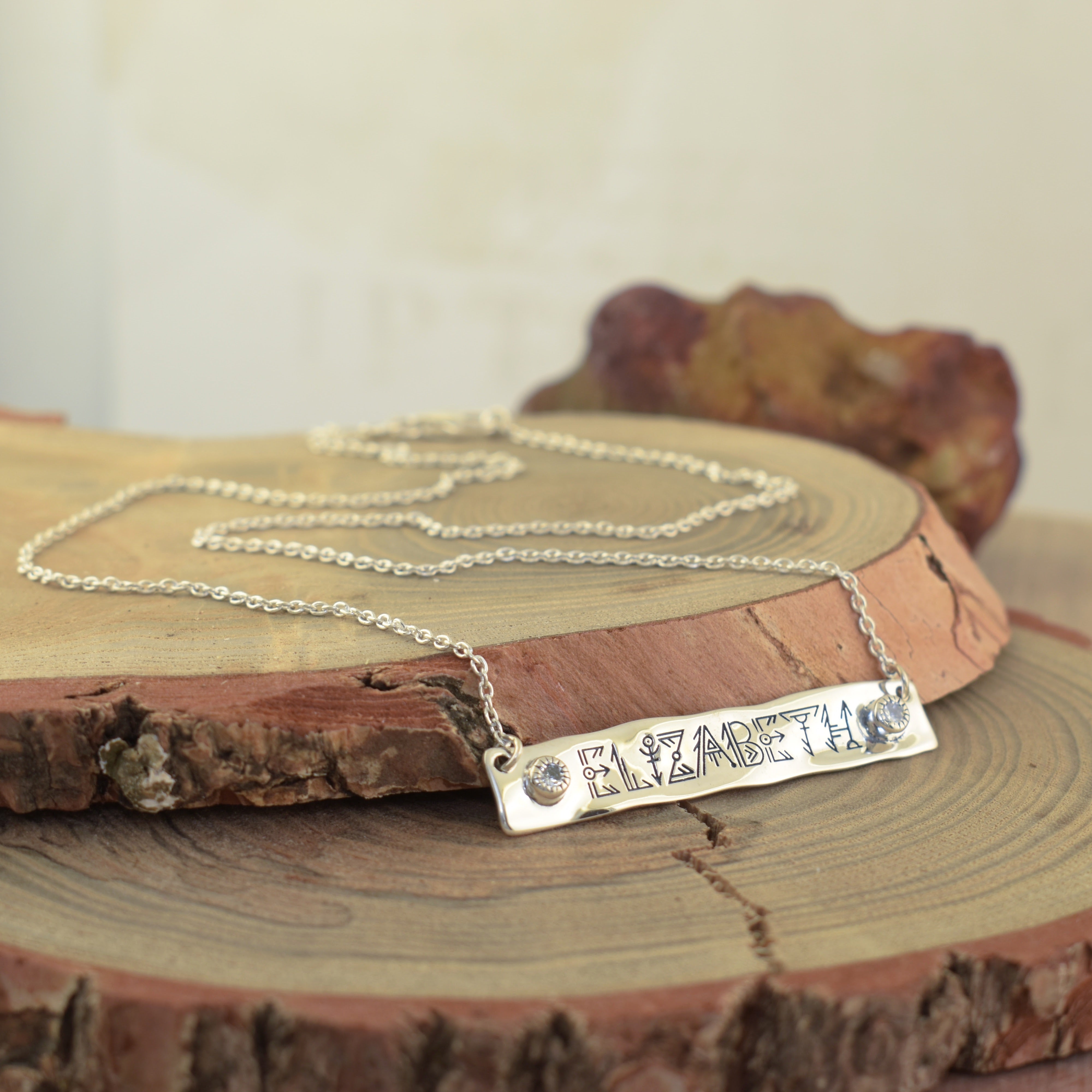 A sterling silver nameplate necklace engraved with the name 'ELIZABETH' and small clear stones on either side