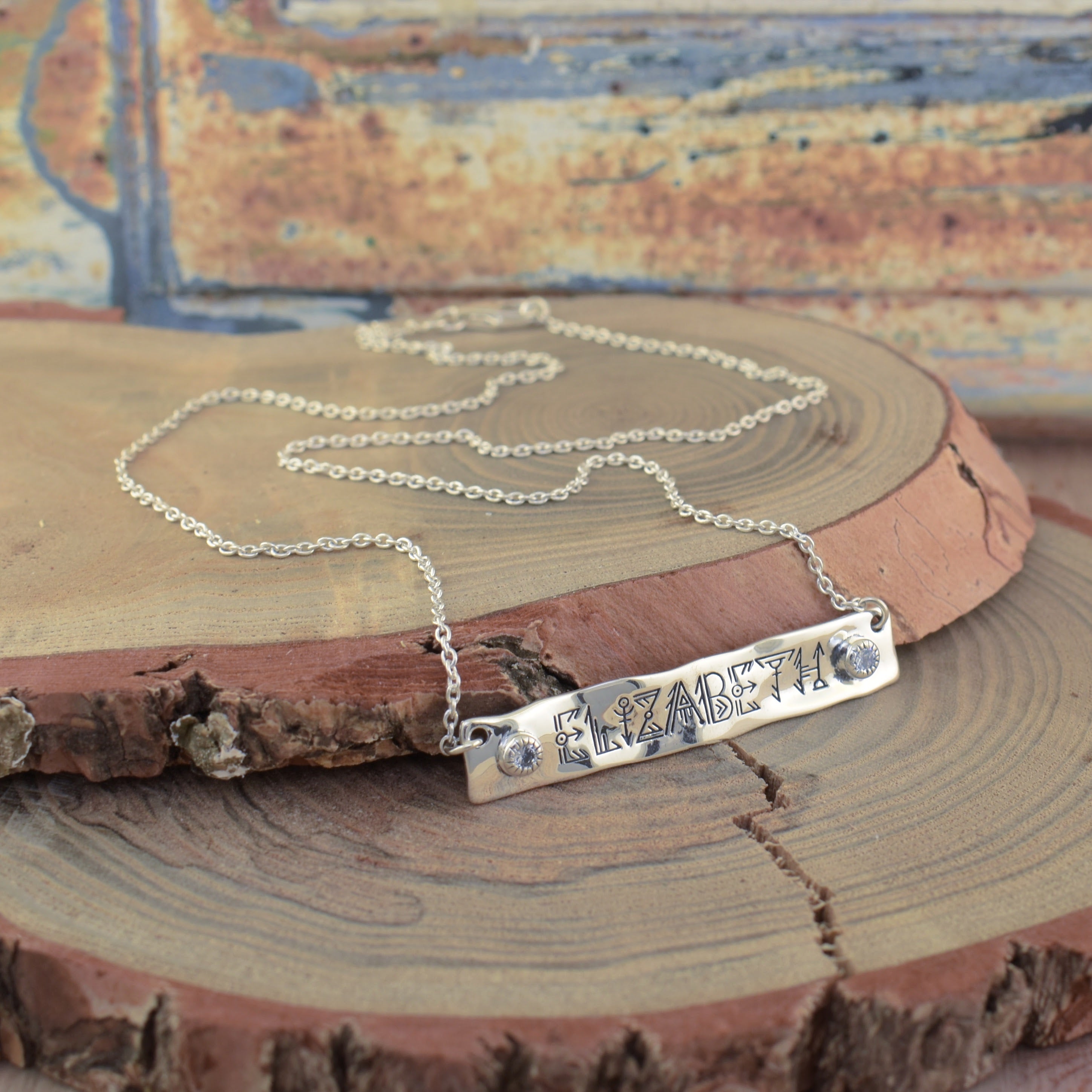 A sterling silver bar necklace engraved with the name 'ELIZABETH' and accented with two small clear stones