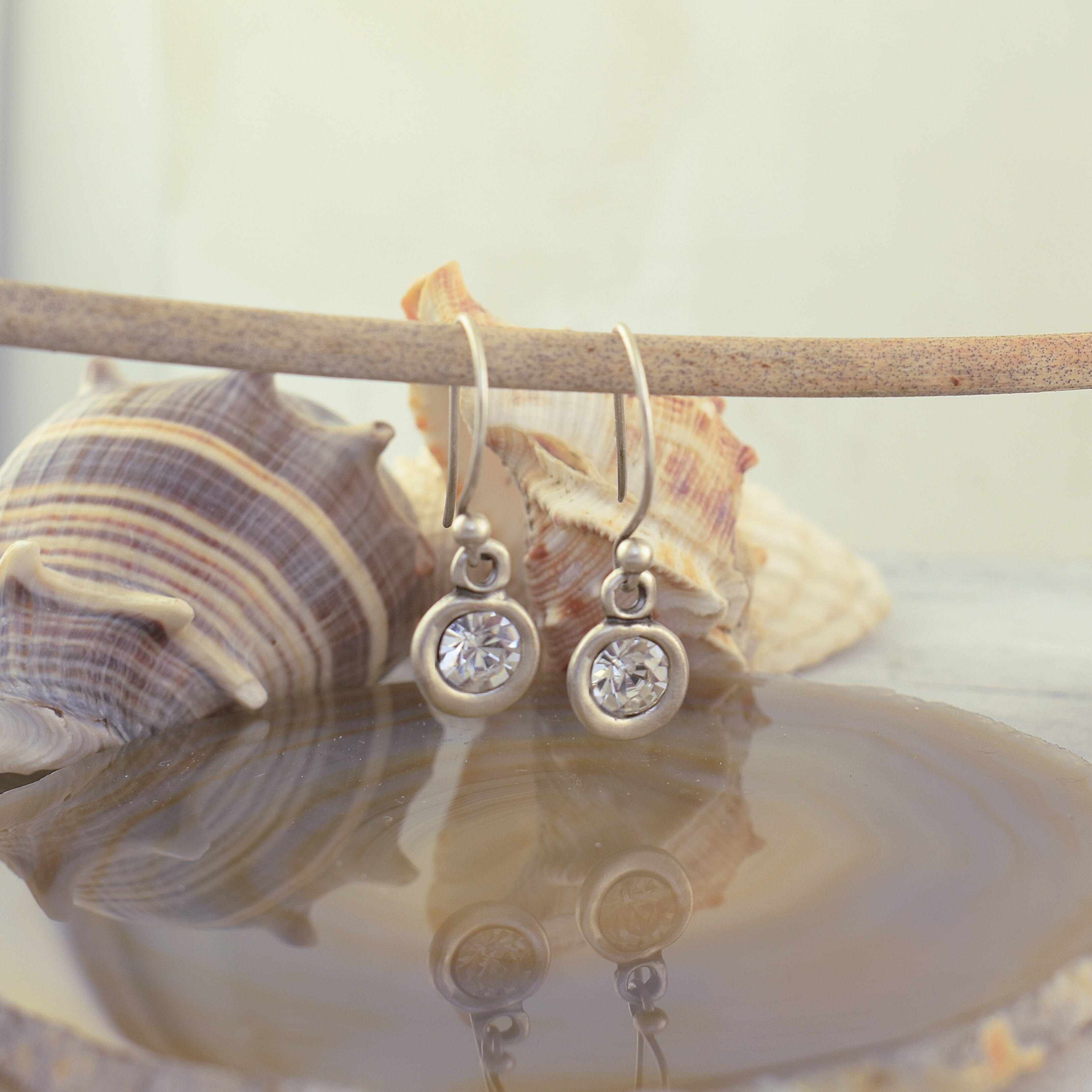 A pair of Zamak drop earrings with round bezel-set clear stones