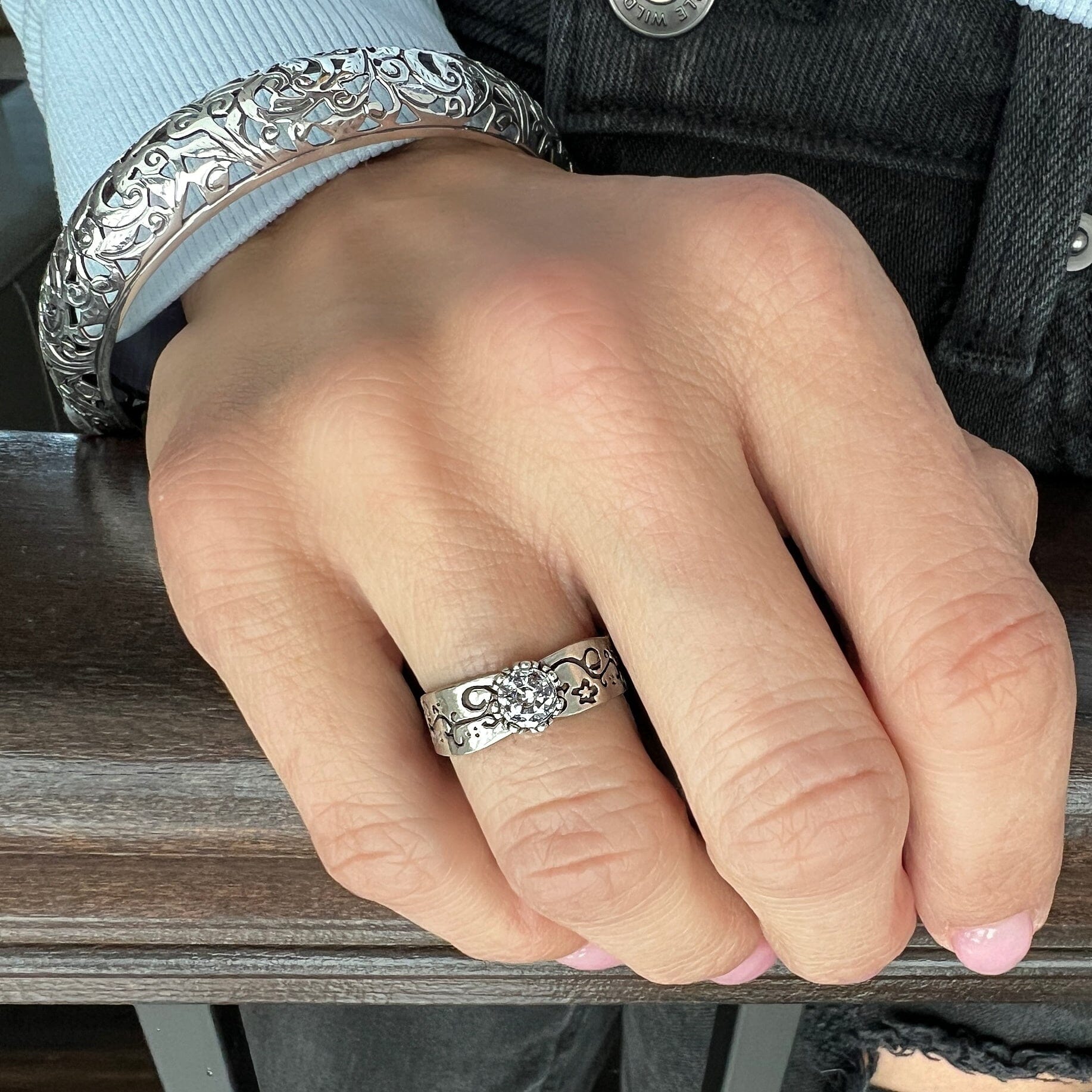 sterling silver ring with floral stamping around the band and a cz stone in the center