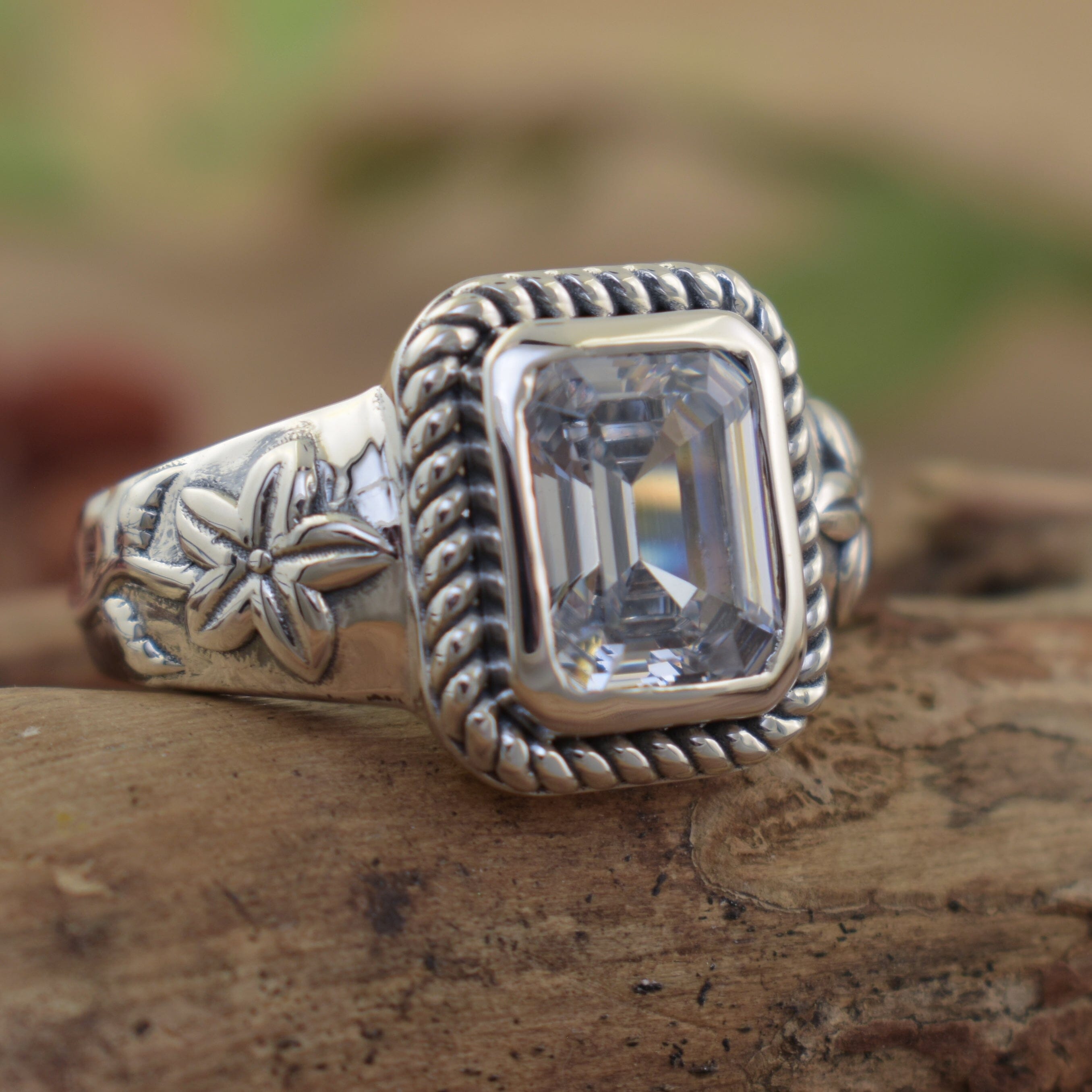 Emerald cut cz stone ring with twisted bezel and floral sterling silver band