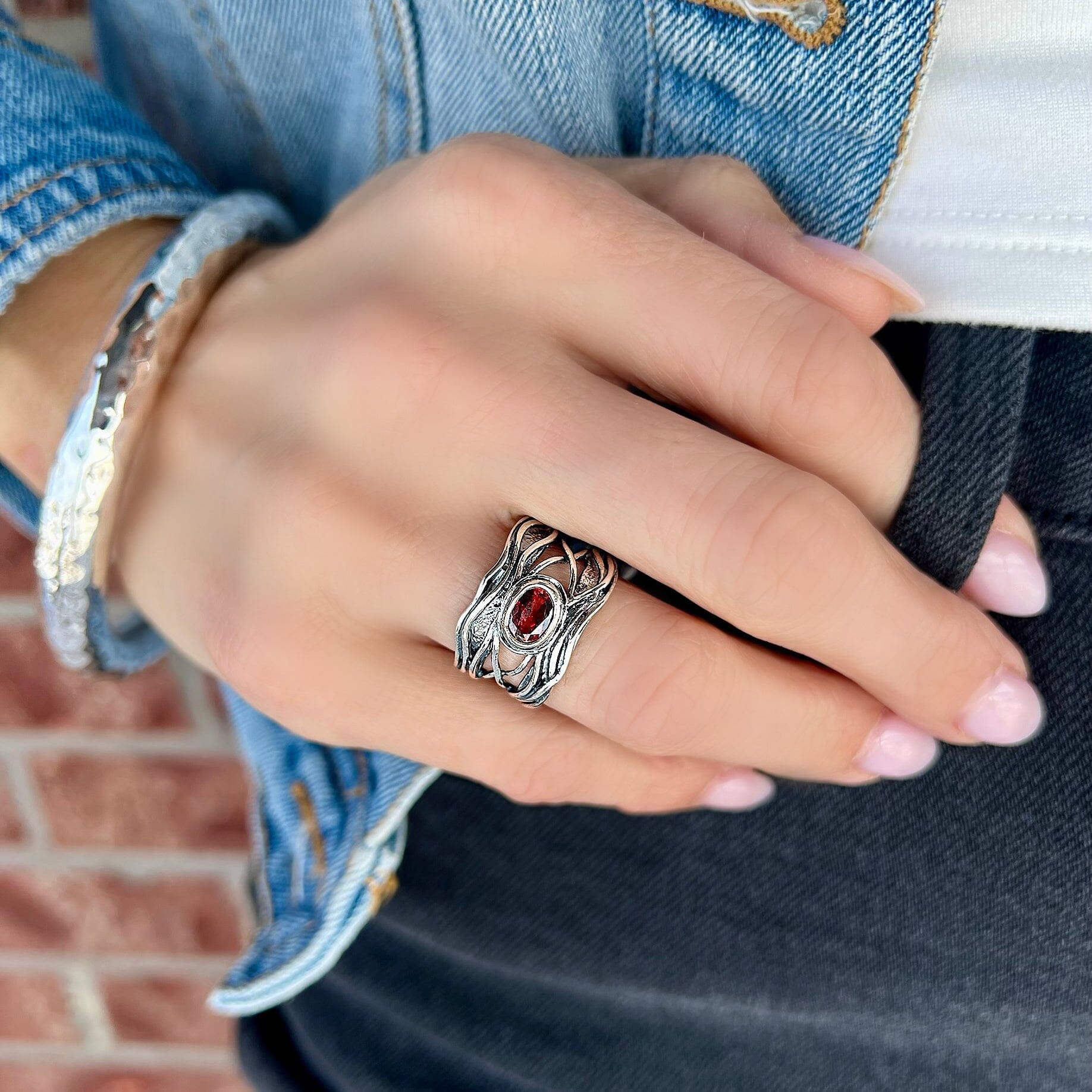 sterling silver ring featuring a garnet stone and a detailed band 