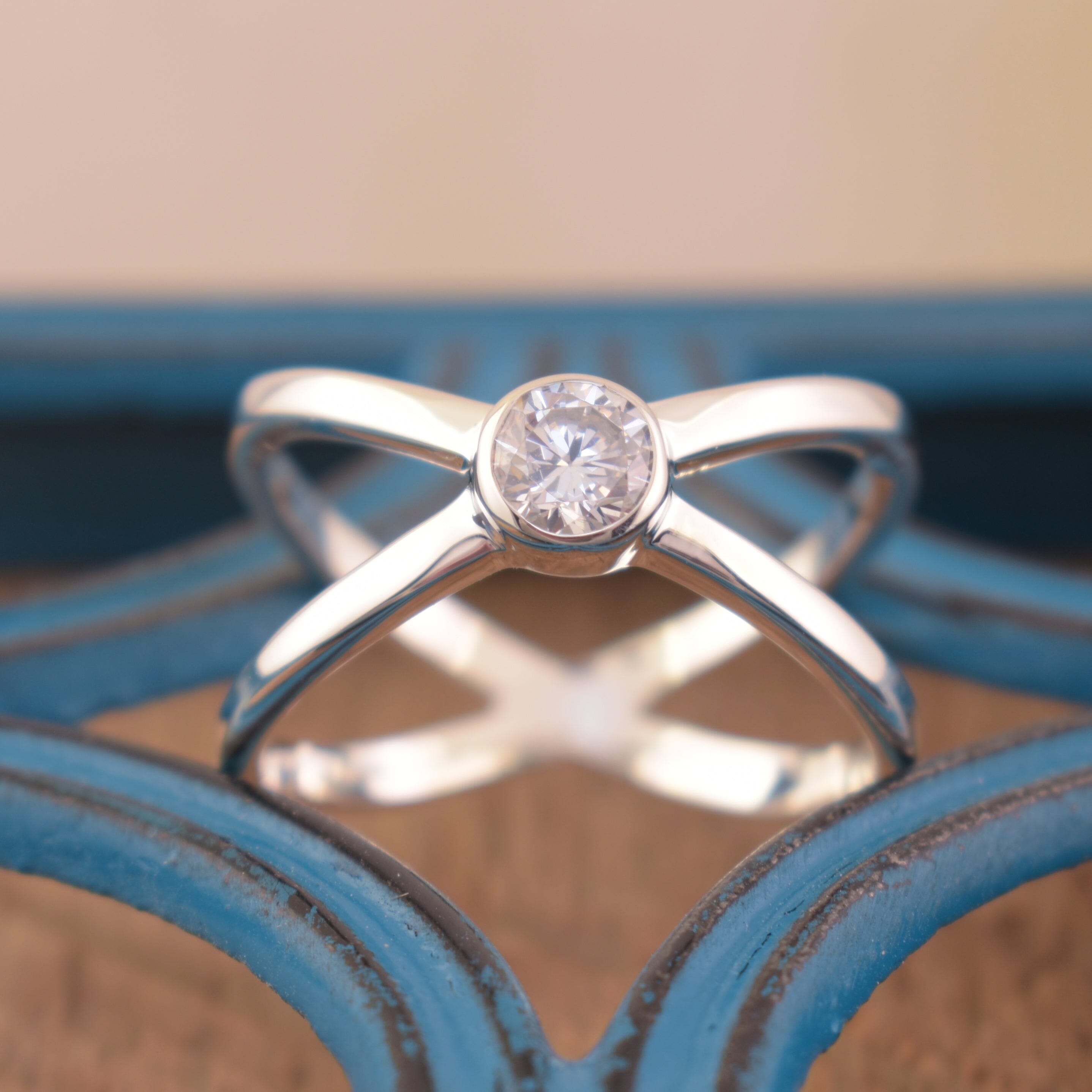 high polished criss cross silver ring with a bezel set cz center