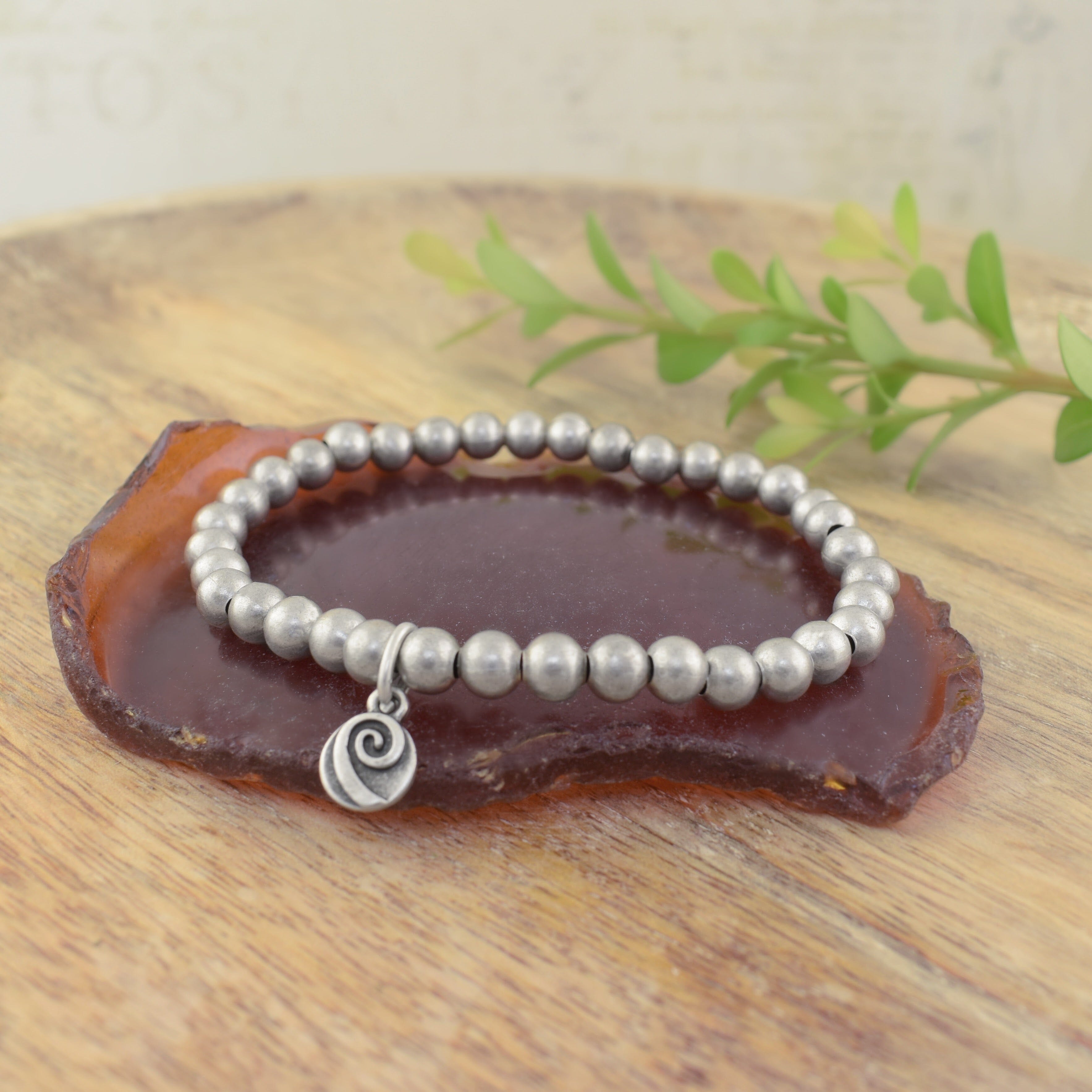 A silver beaded bracelet with a logo charm