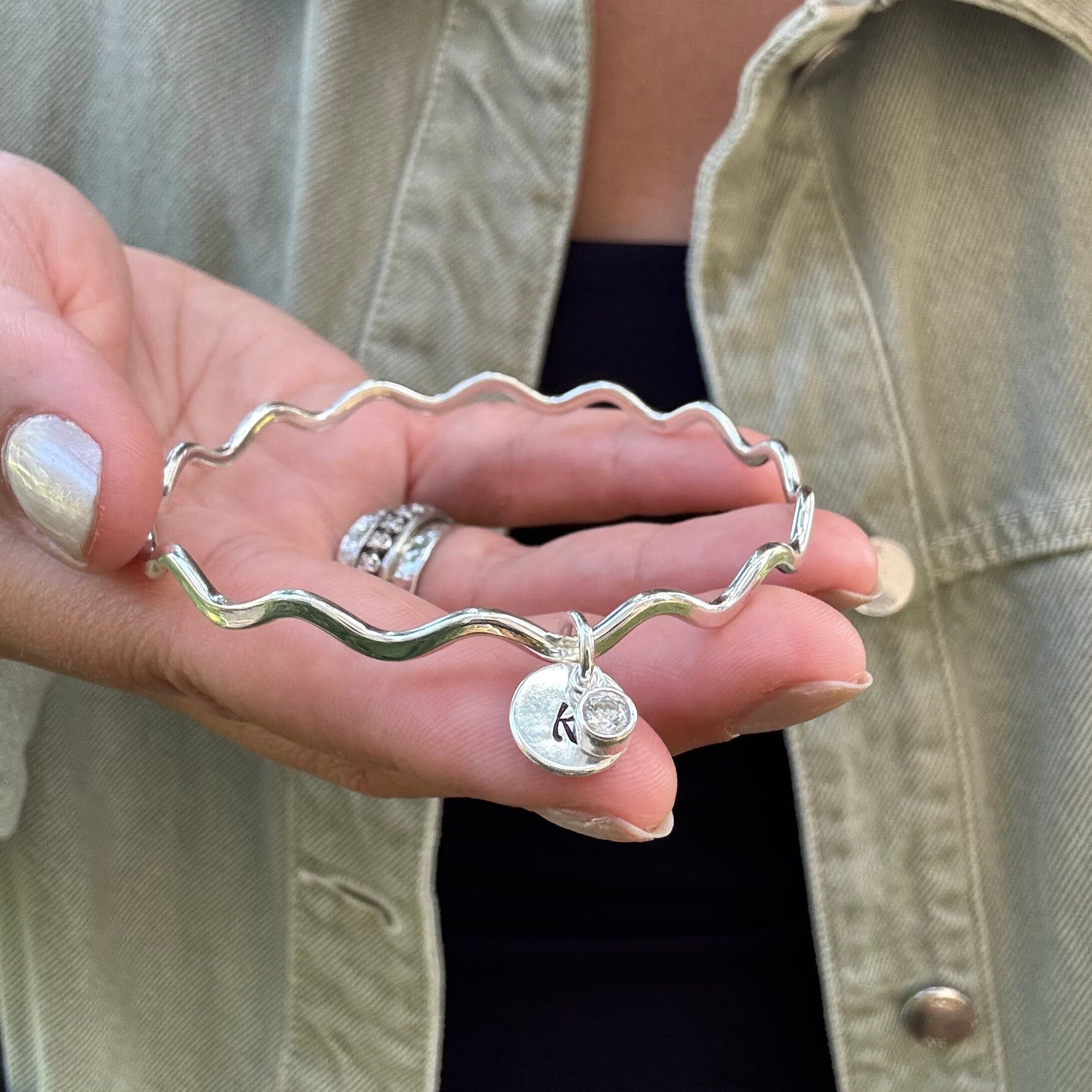 Keepsakes initial bangle with a cz dangle laying on top