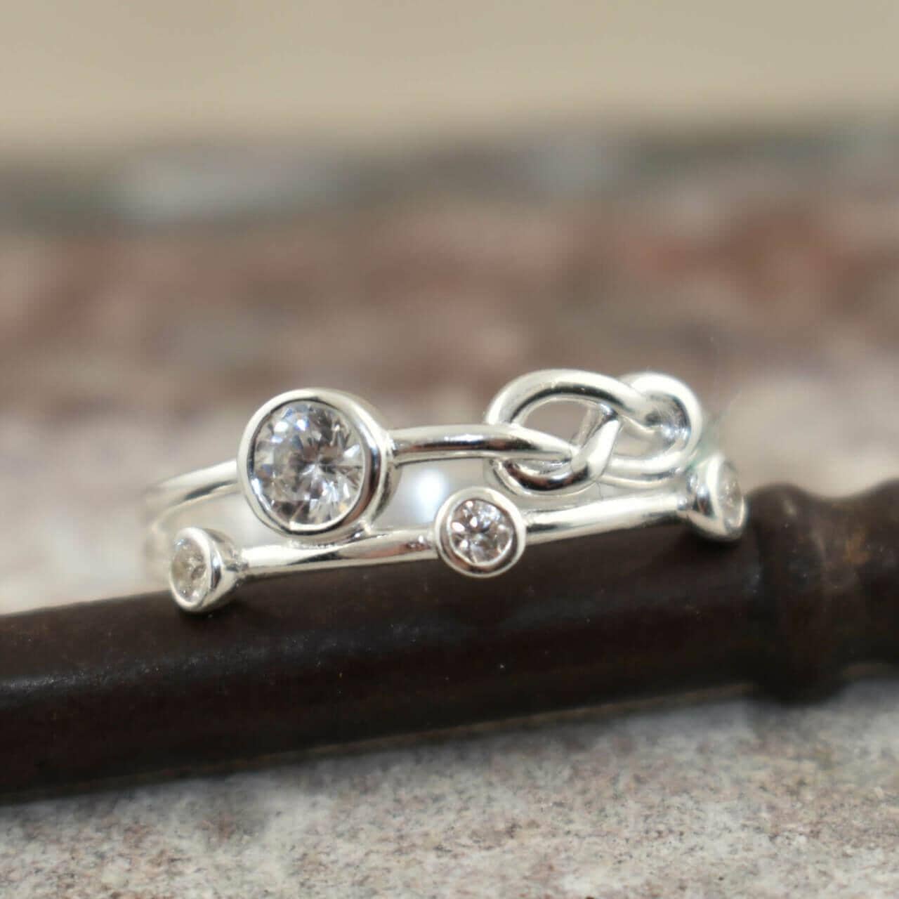 A sterling silver ring featuring small round CZ stones and a knot design in the band