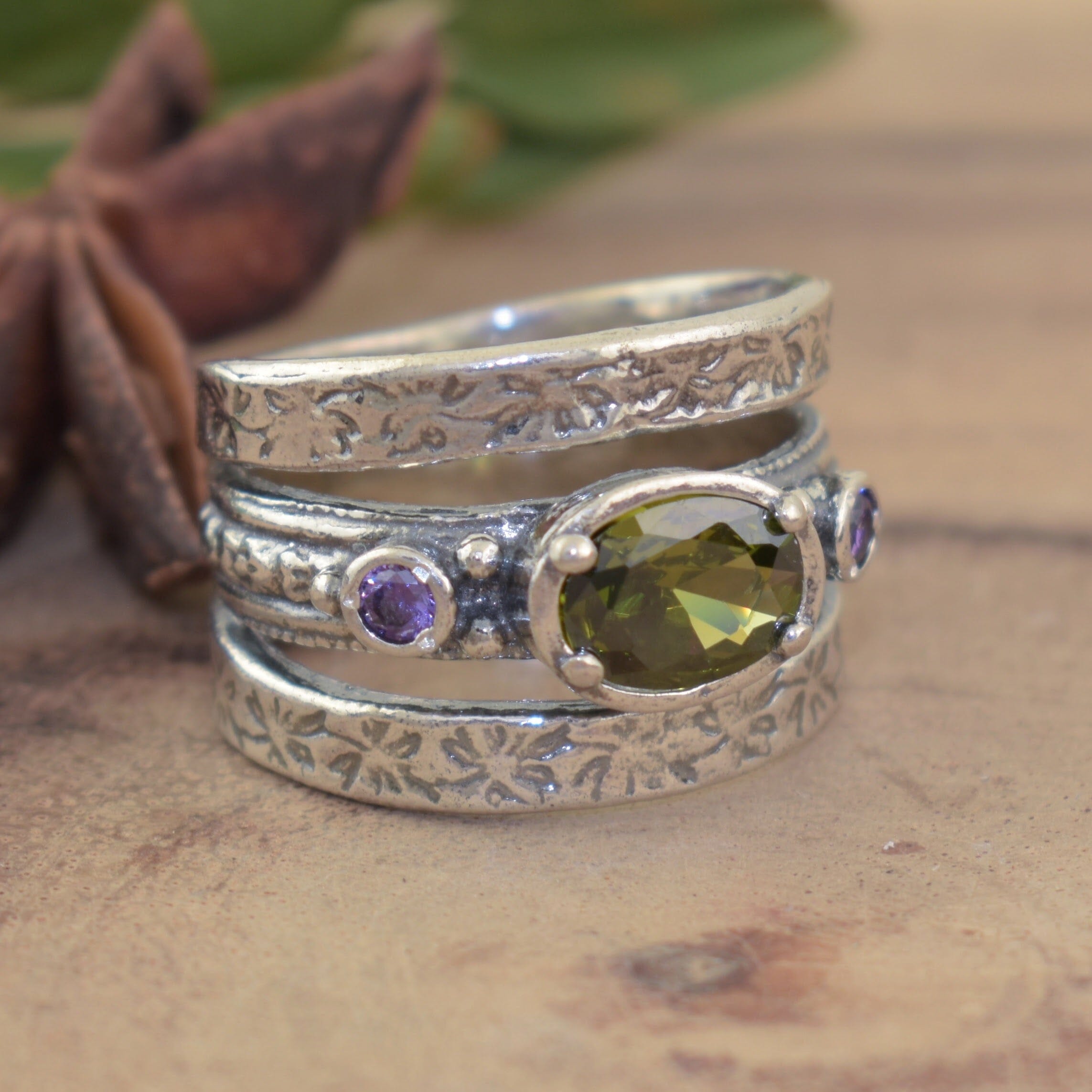 Hand crafted ring featuring two amethyst stones and one peridot