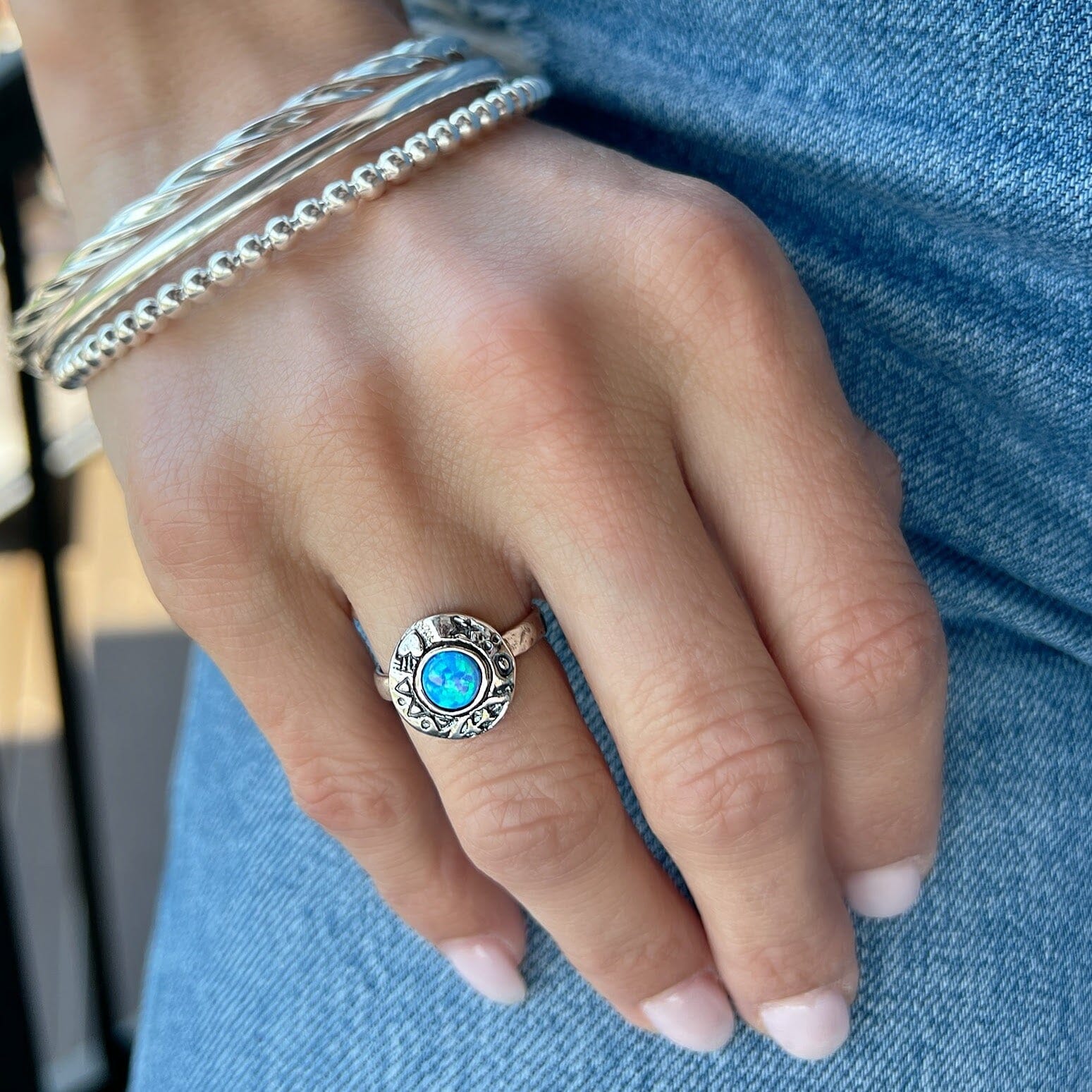 blue green opal ring bezel set in a round sterling silver frame with oxidized stamped details