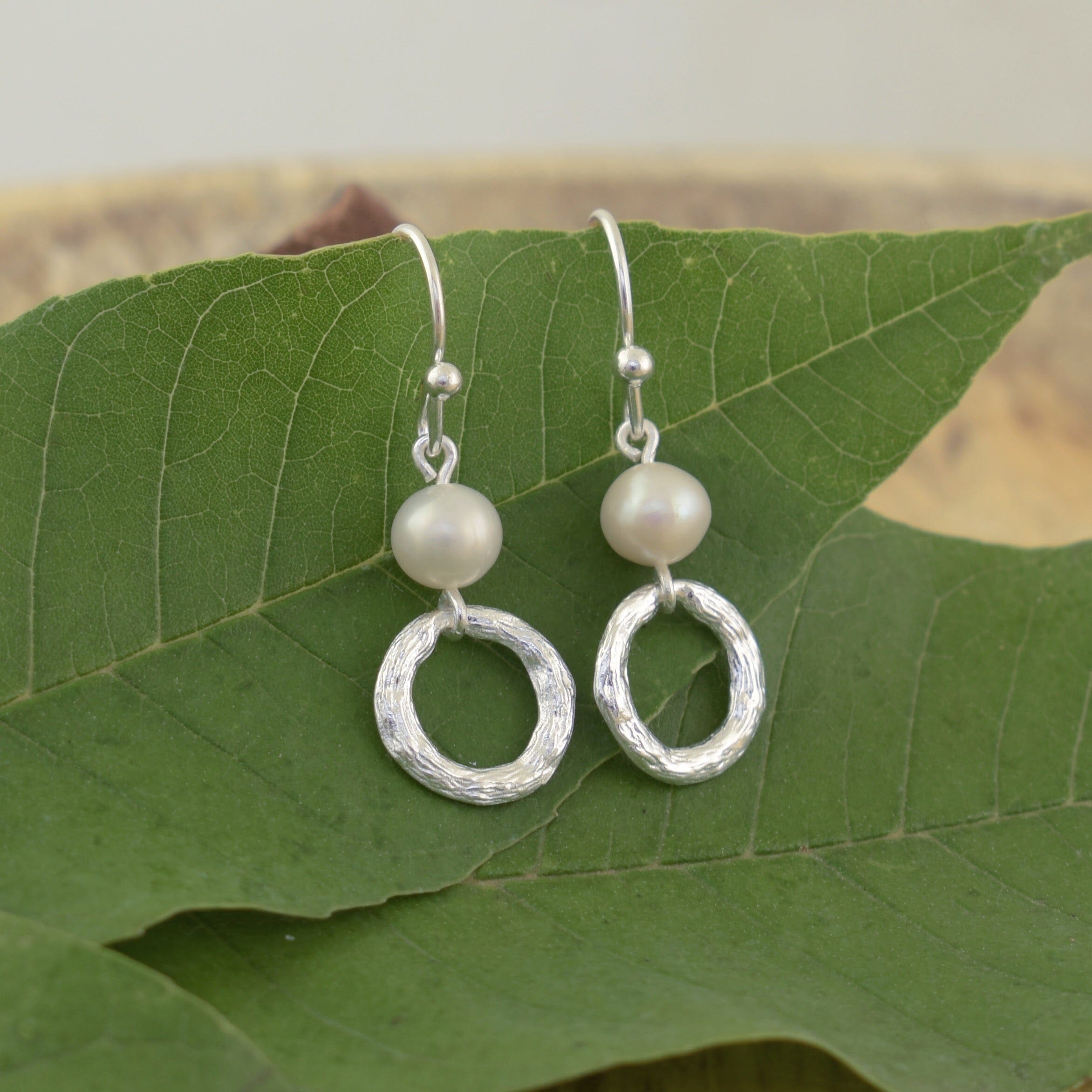freshwater pearl earrings with dangling circles with a brushed texture