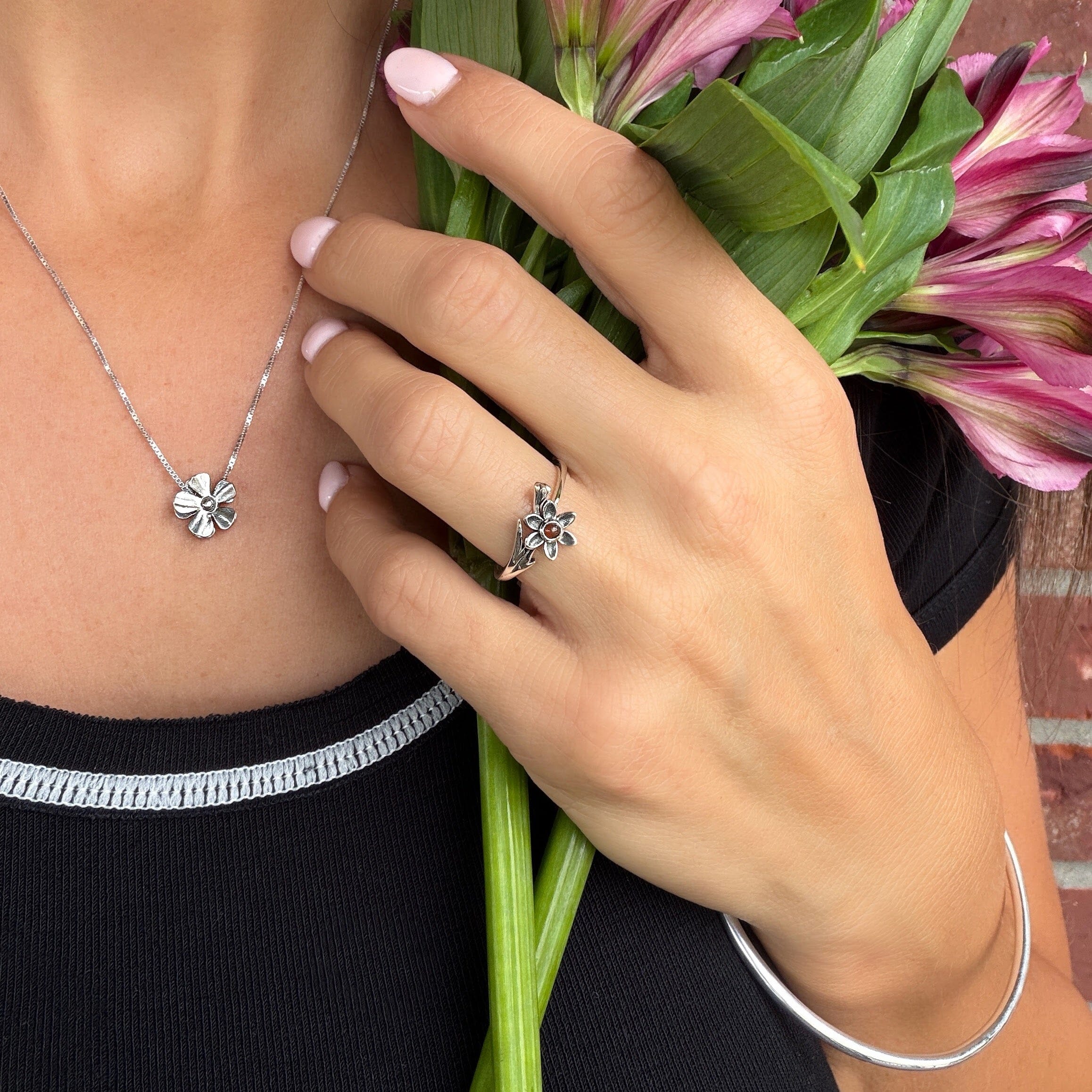 a small ruby red stone bezel set in a sterling silver flower ring