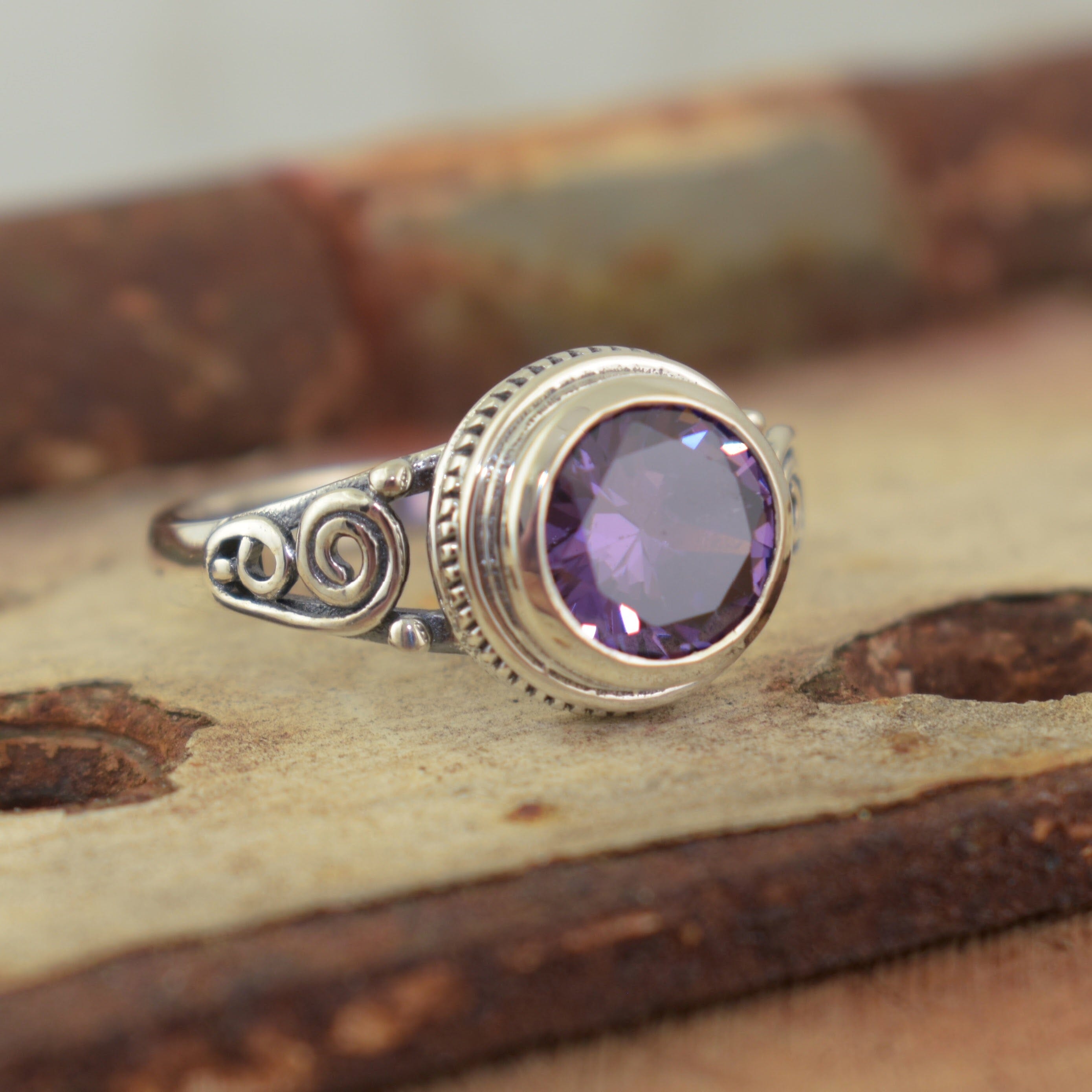 Swirl designed band featuring a purple CZ stone