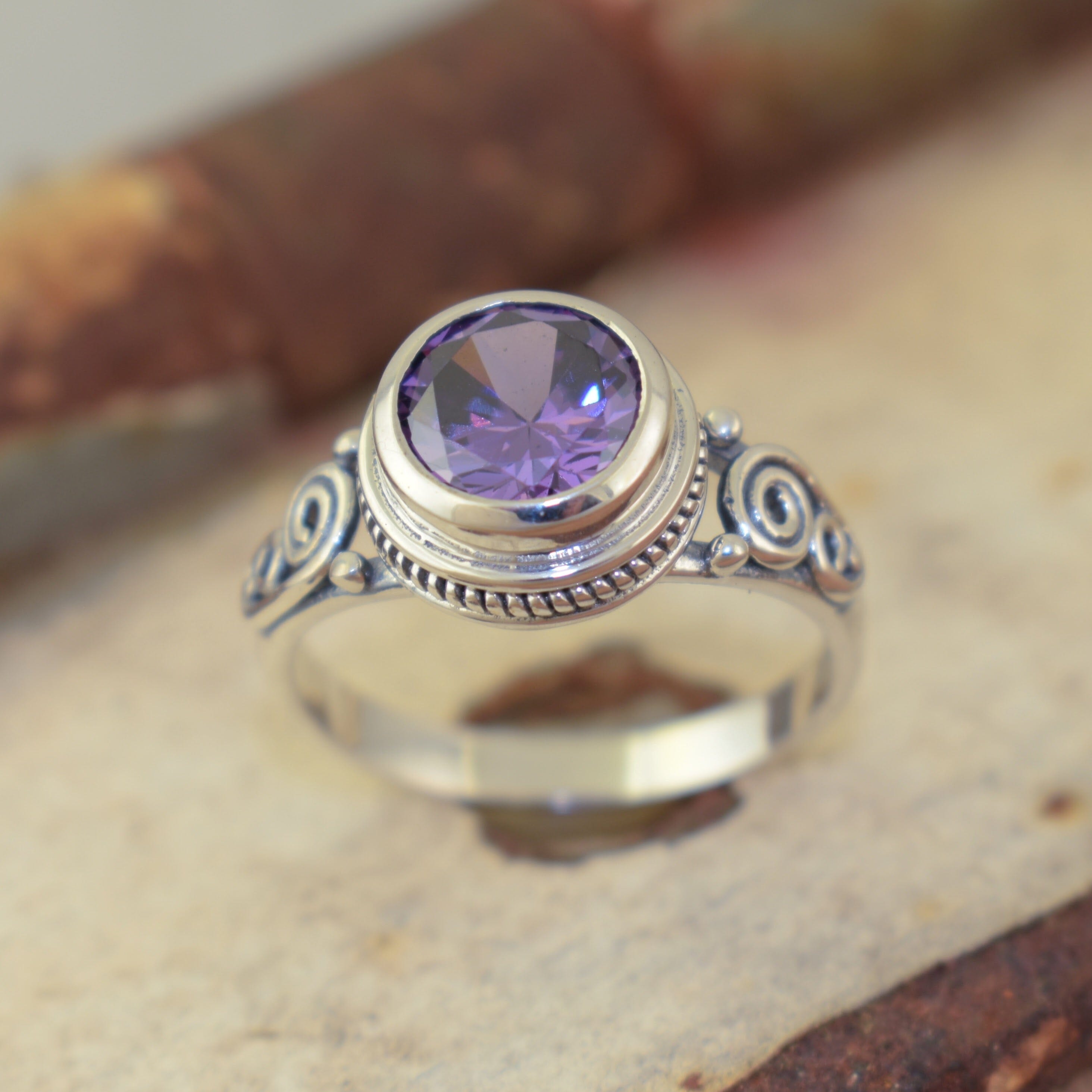 Round bezel set CZ stone with a swirl band design