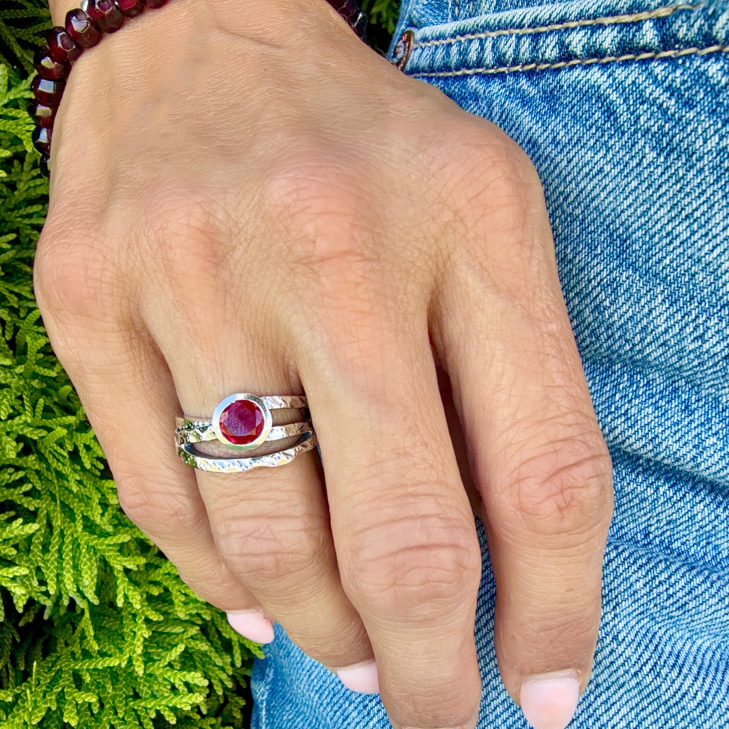 sterling silver ring with crisscross bands featuring a ruby cz stone bezel set