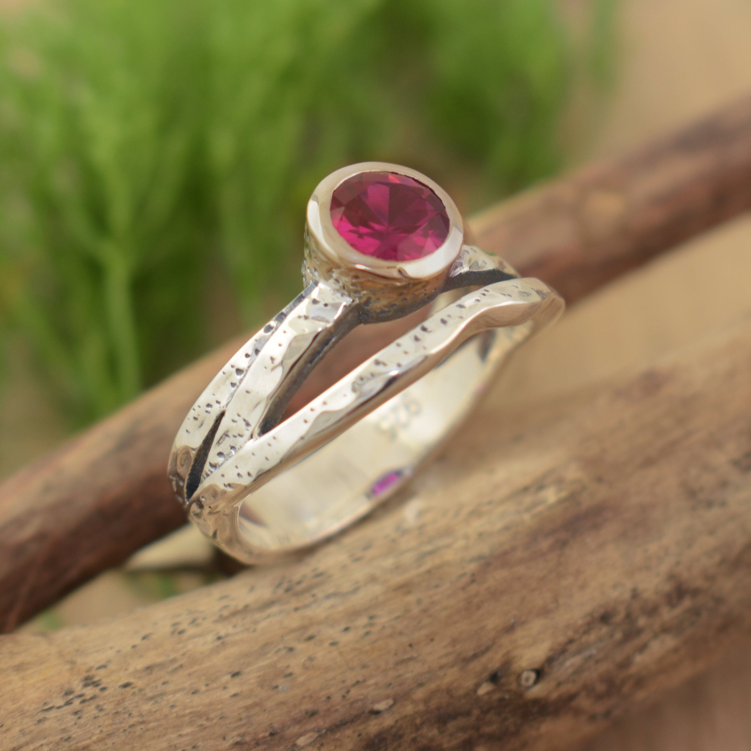 organic sterling silver band featuring a bezel set ruby cz center