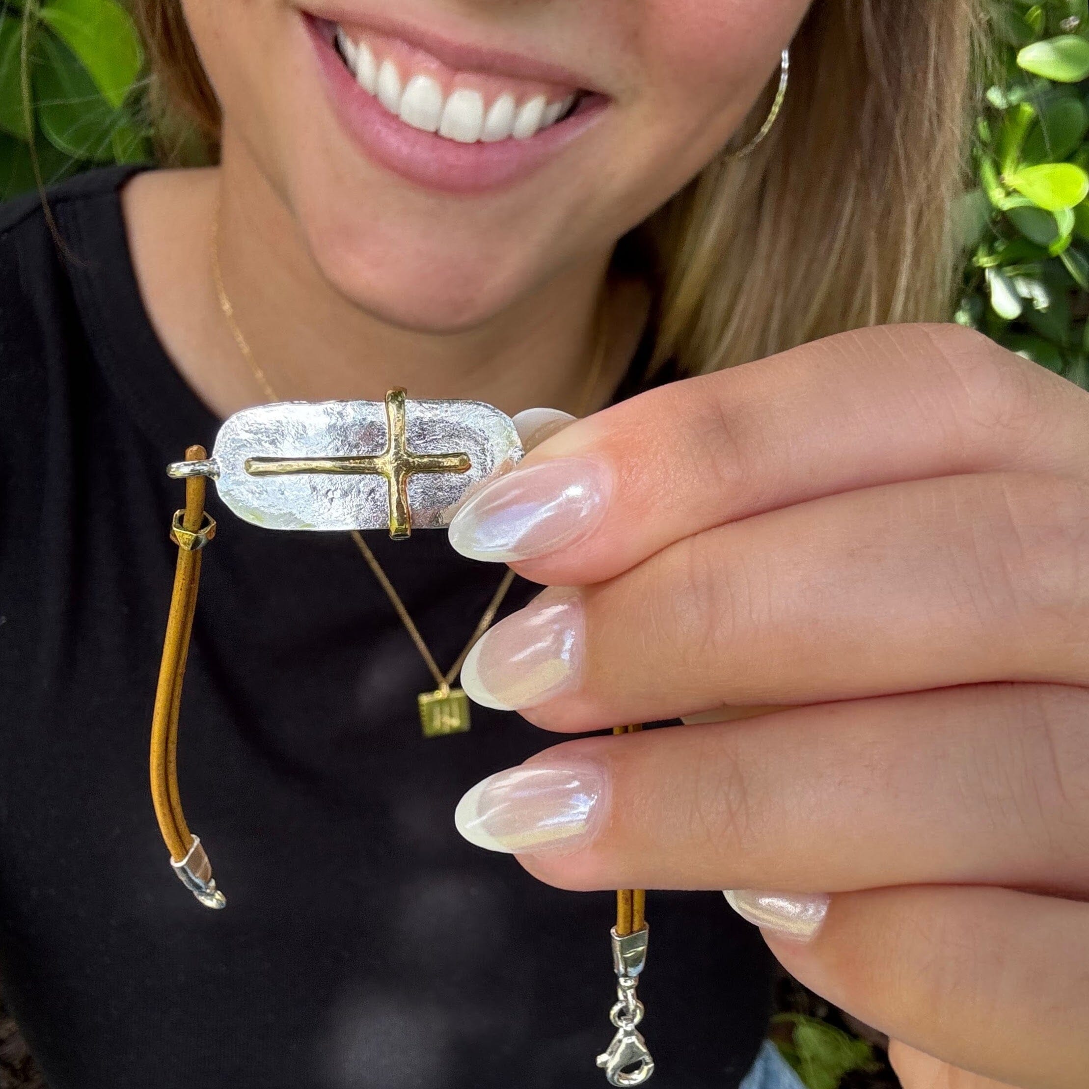 leather bracelet featuring a sterling silver bar with a brass cross