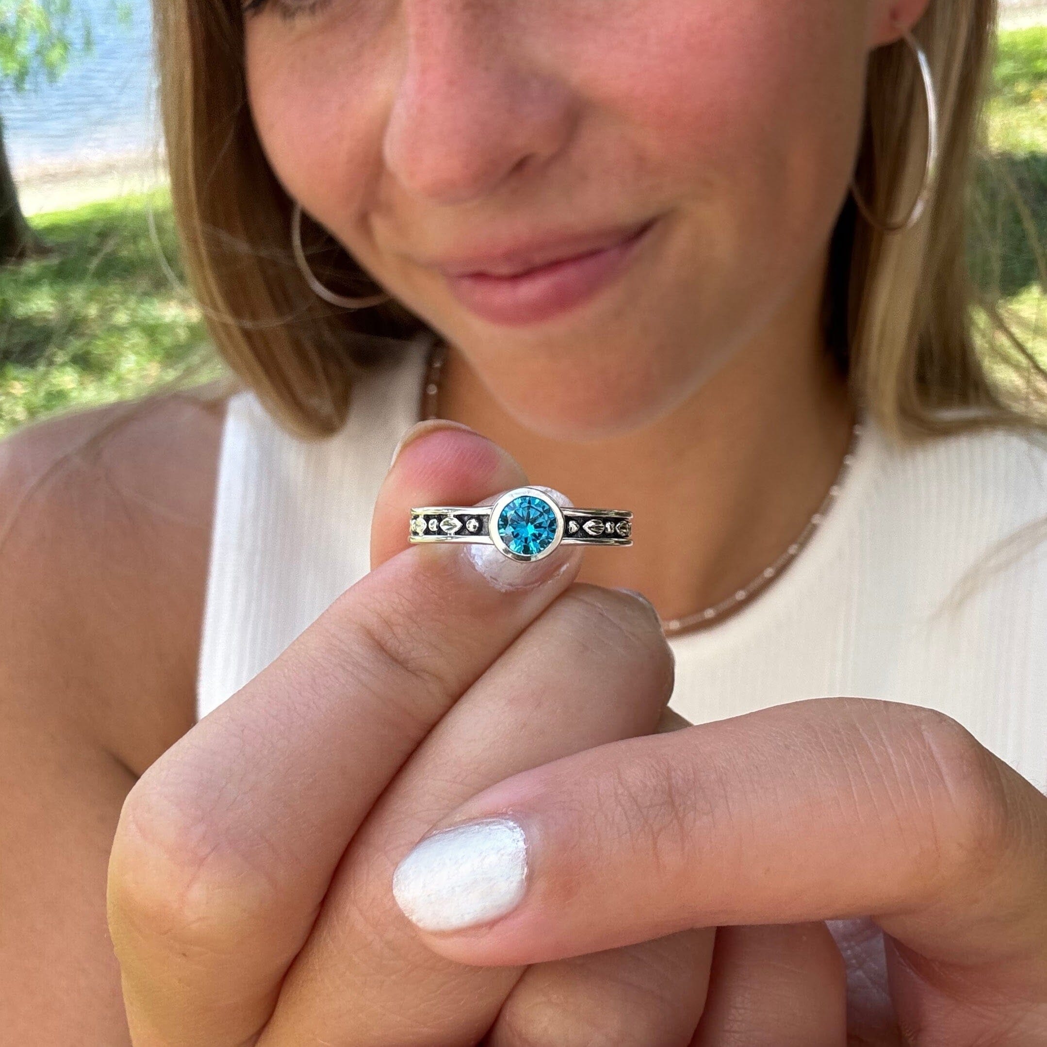 thin silver ring featuring high polished details on an oxidized background with a blue center stone