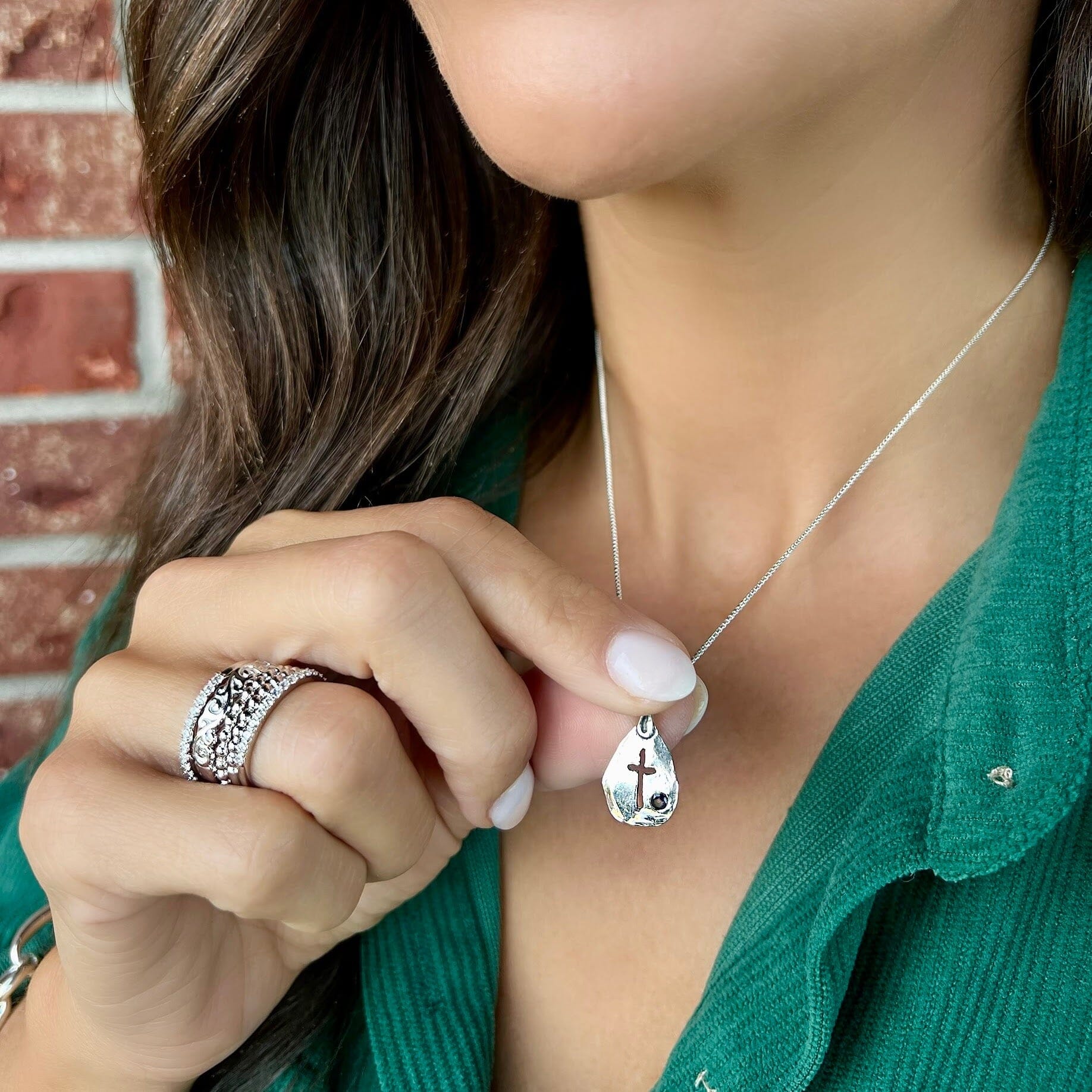 dainty silver necklace pendant featuring a cutout cross and gemstone