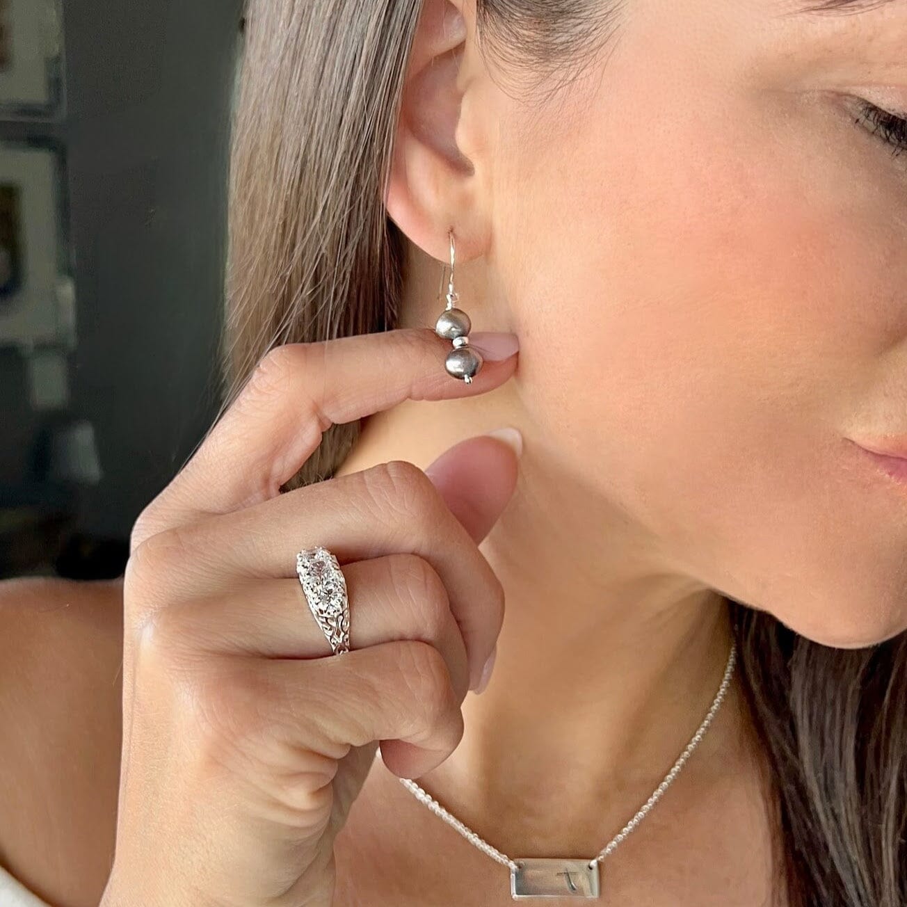 two medium freshwater pearls in gray strung on a sterling silver french wire earring hook