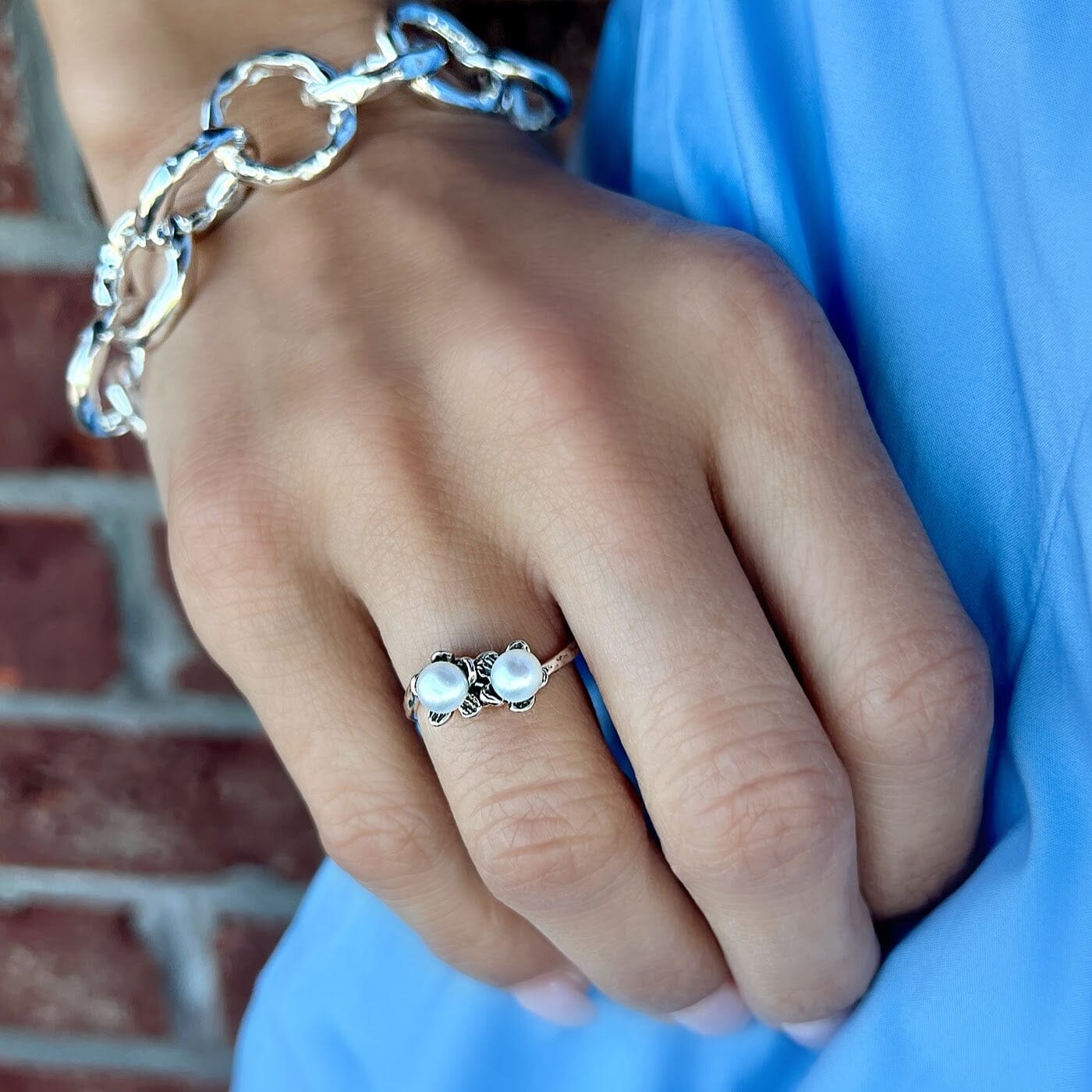 dainty silver ring featuring two flowers with freshwater pearl centers