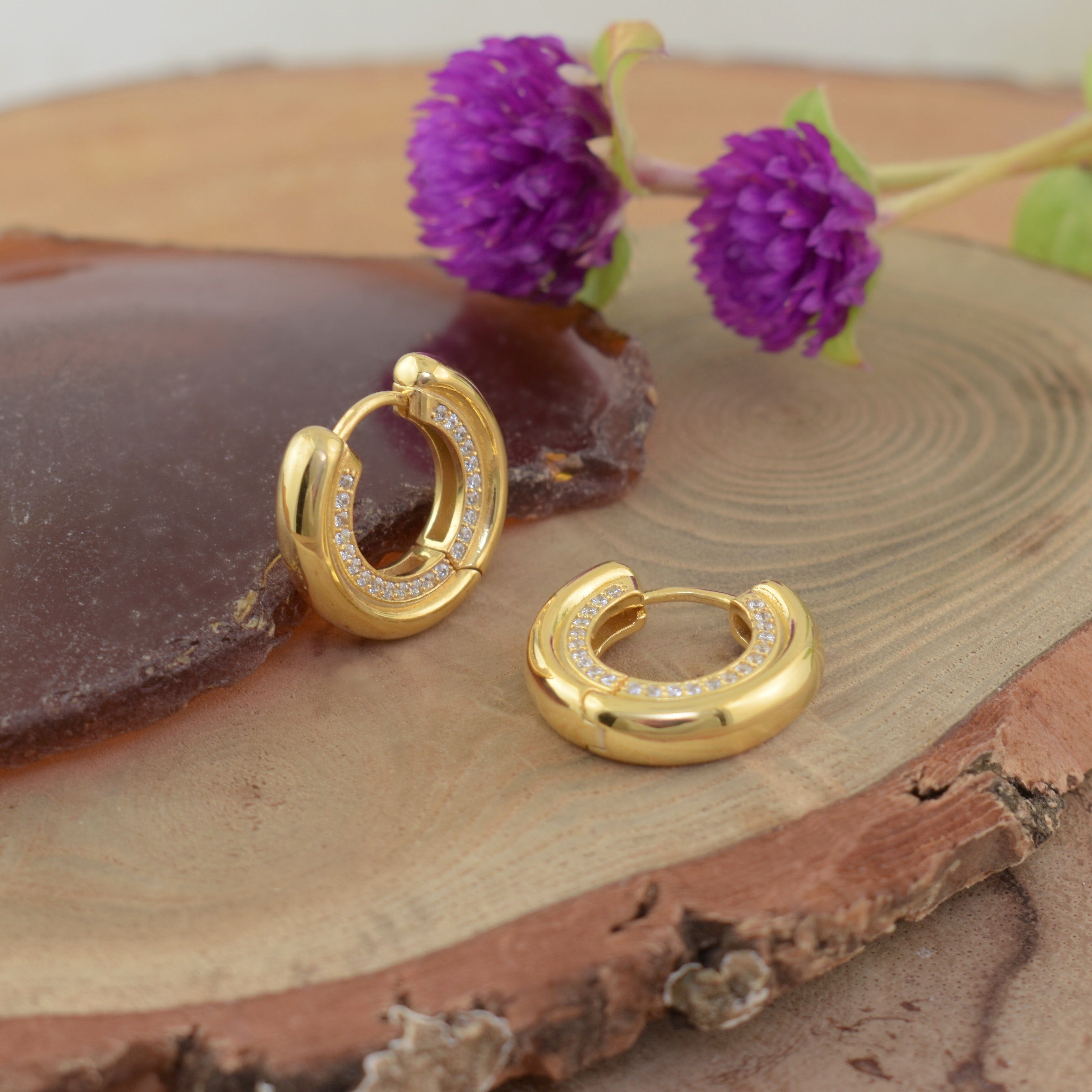 a pair of polished gold hoop earrings with small clear stones along the front curve