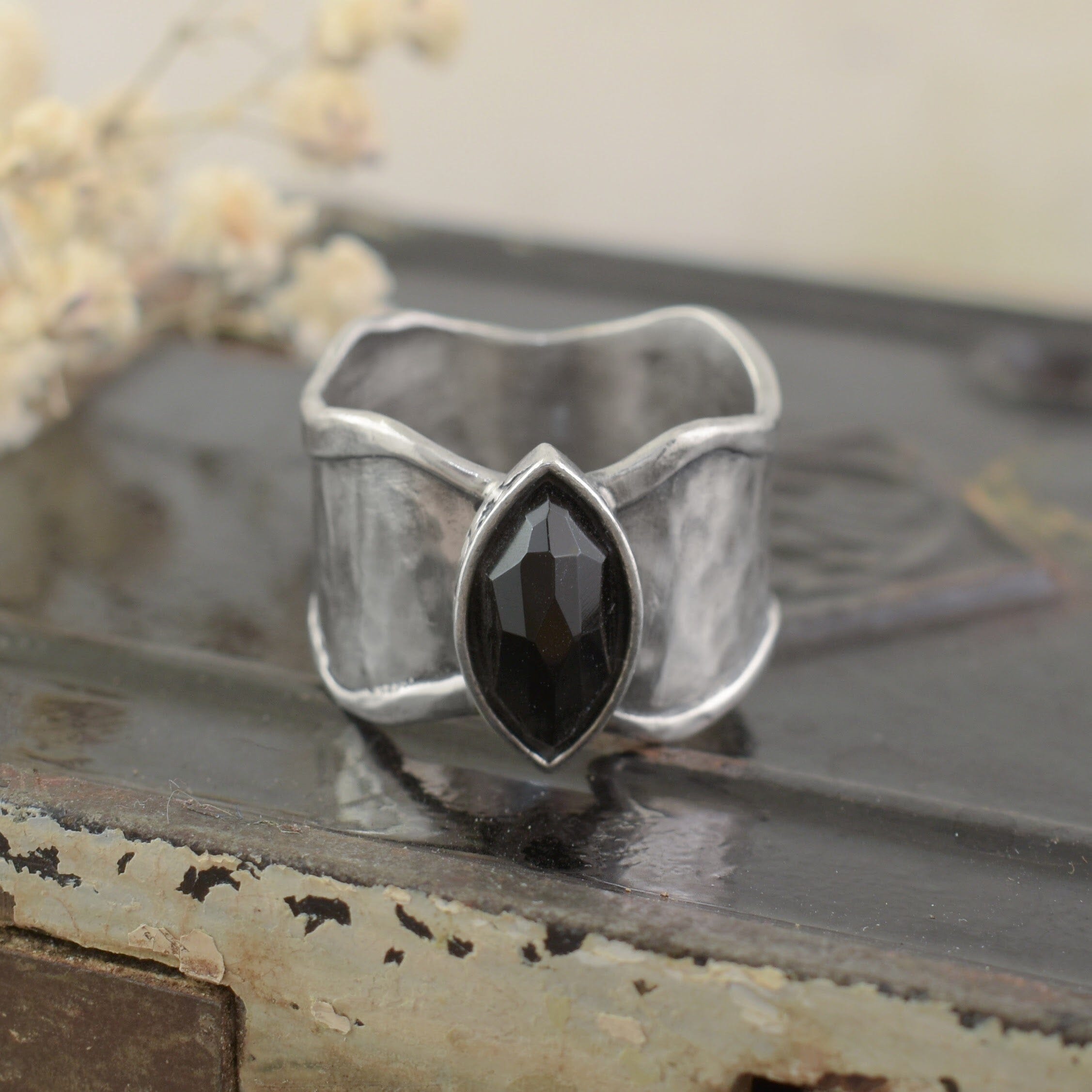 A sterling silver ring with an organic thicker band, featuring a black onyx marquise-cut stone in the center