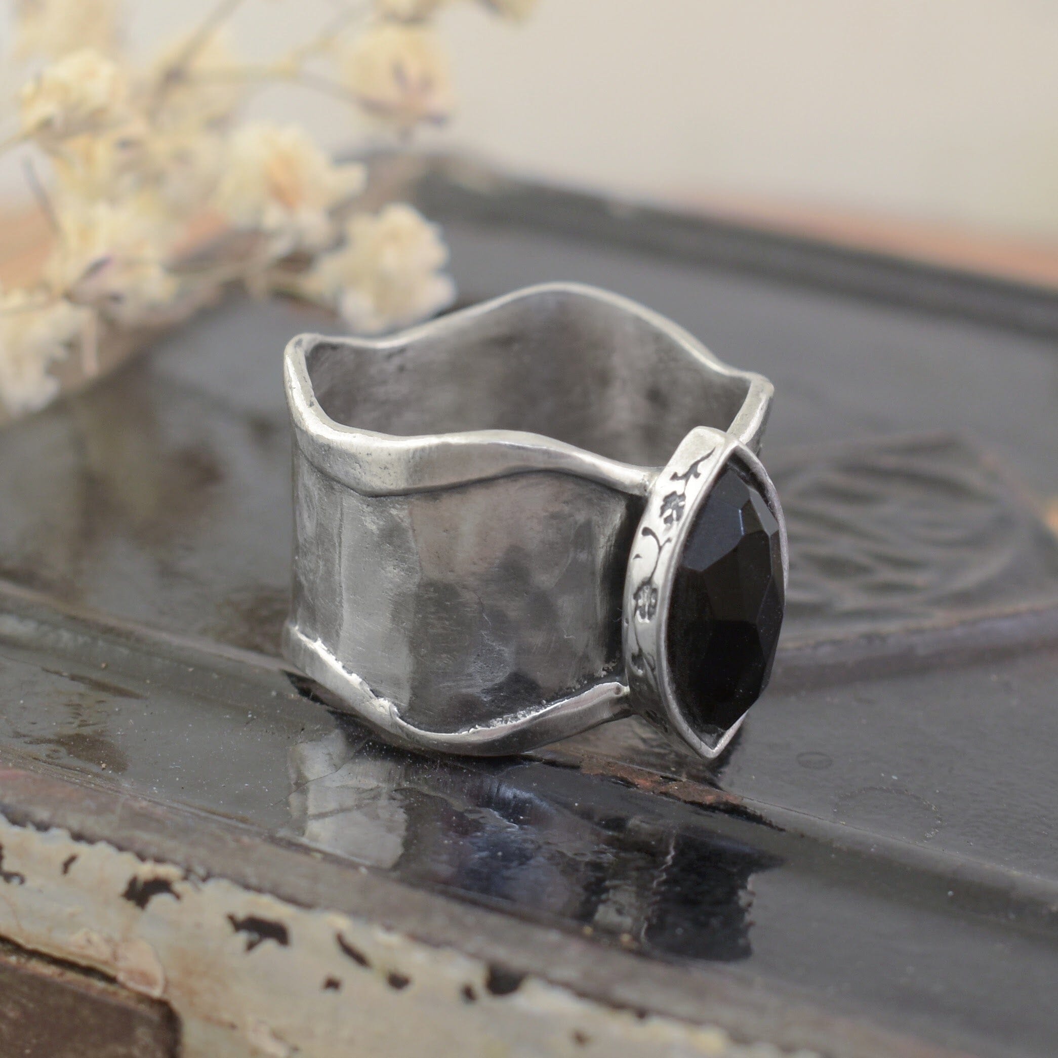 A sterling silver ring with an organic thicker band, featuring a black onyx marquise-cut stone in the center