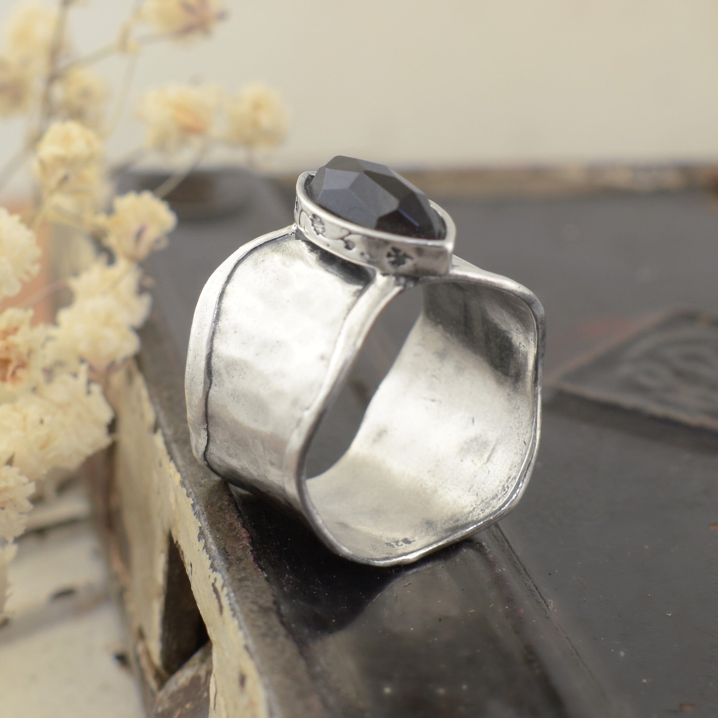 A sterling silver ring with an organic thicker band, featuring a black onyx marquise-cut stone in the center