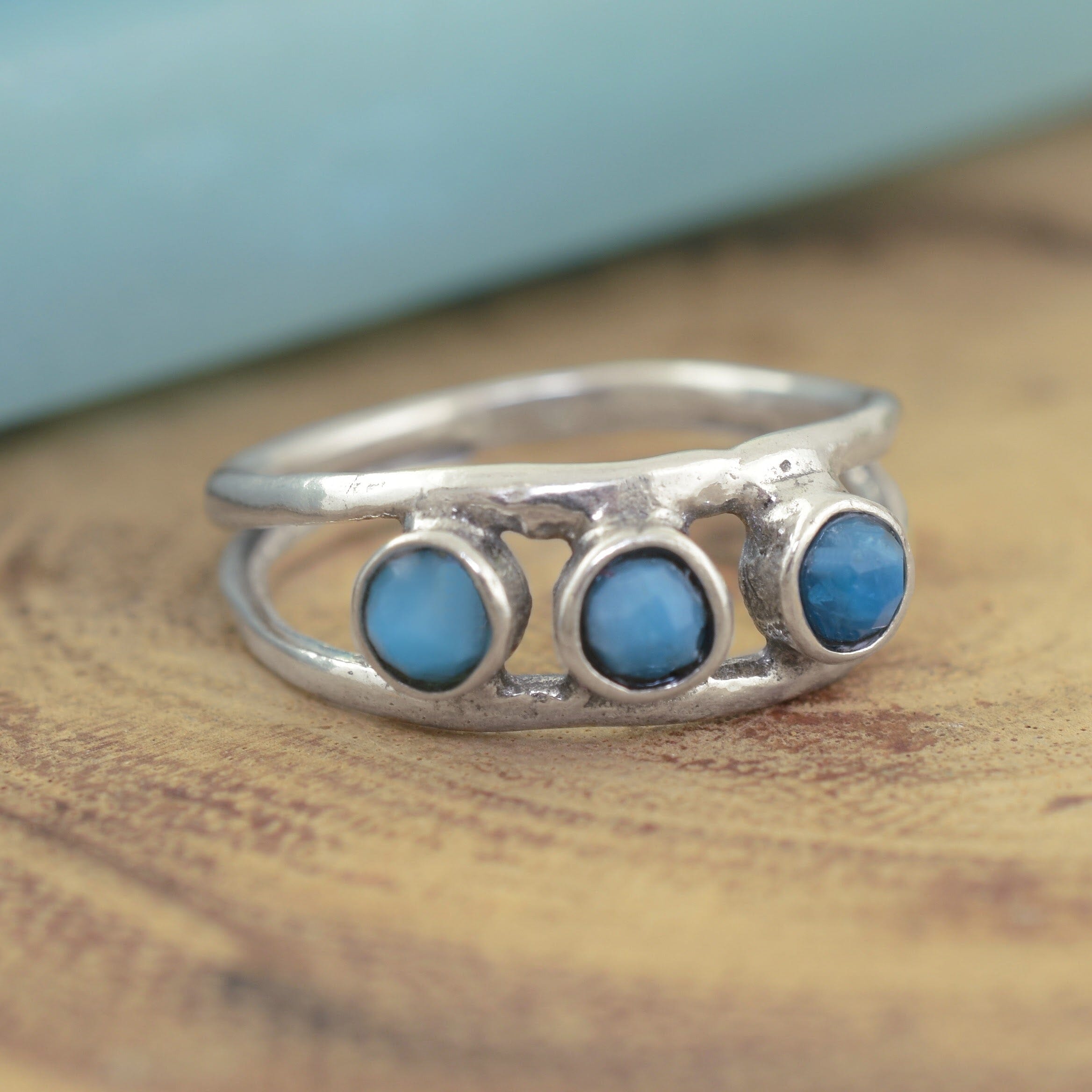 A sterling silver ring featuring 3 small blue beads running along the middle