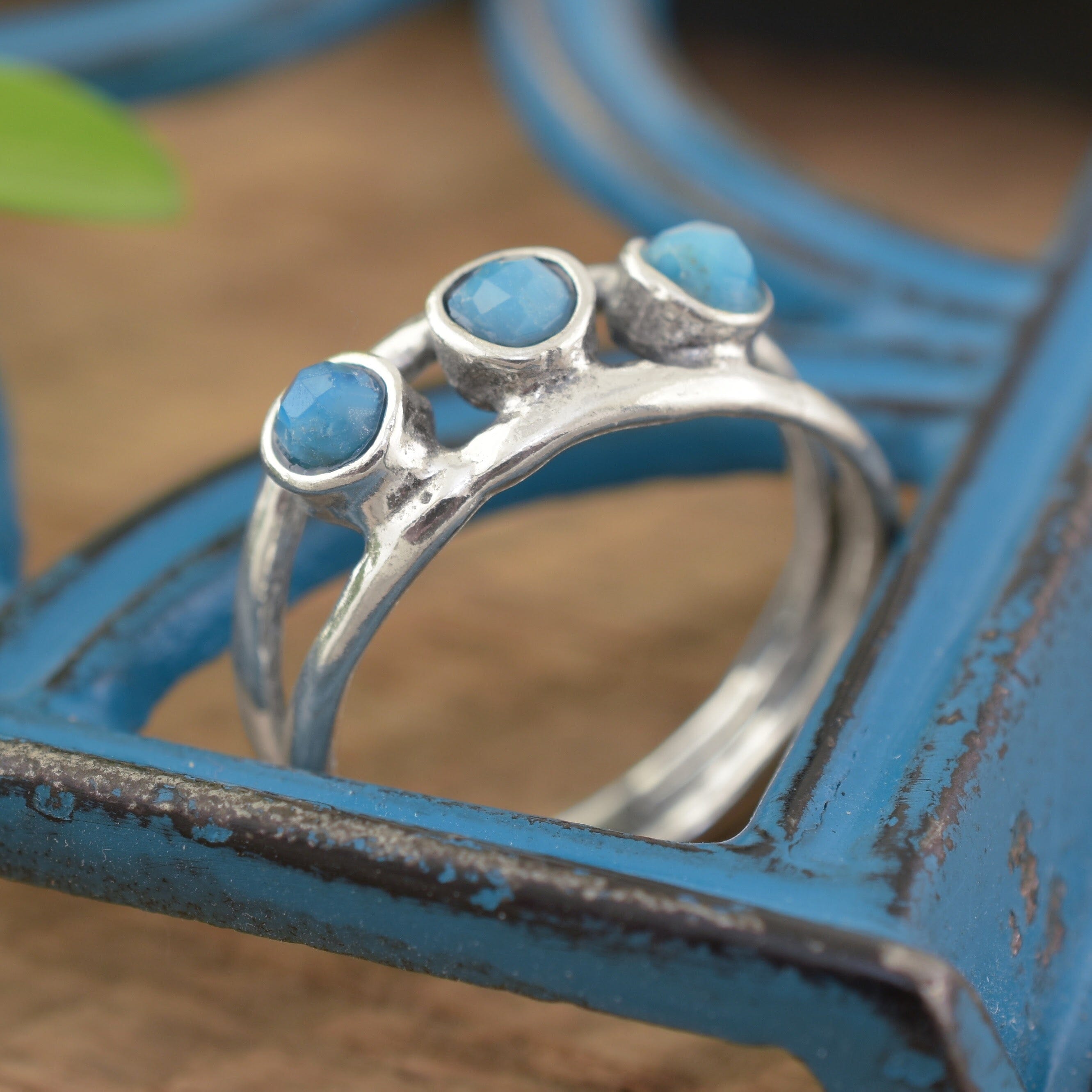 A sterling silver ring featuring 3 small blue beads running along the middle